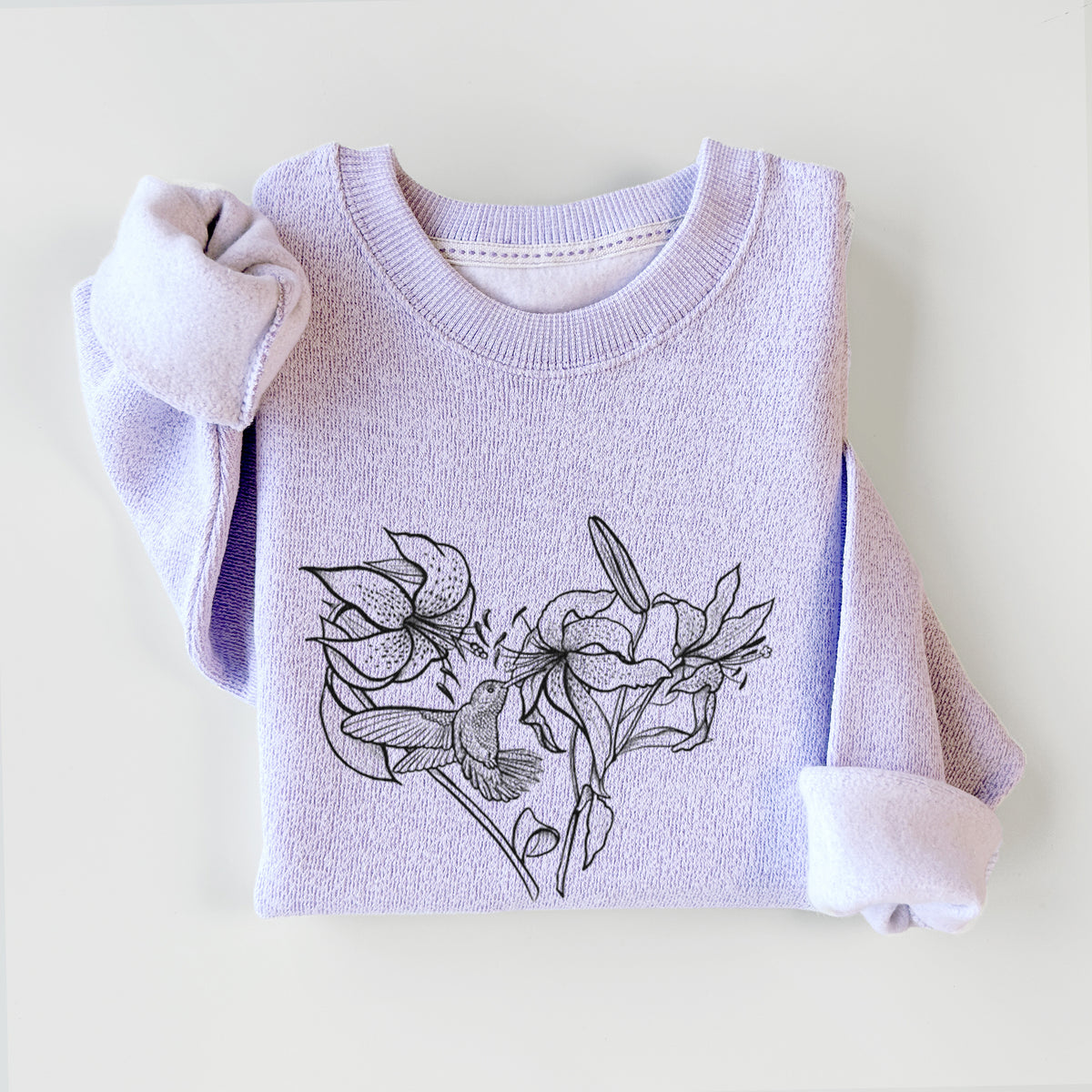 Ice purple knit sweatshirt printed with a black ink line drawing of lilies and a hummingbird arranged in a heart shape, styled flat.