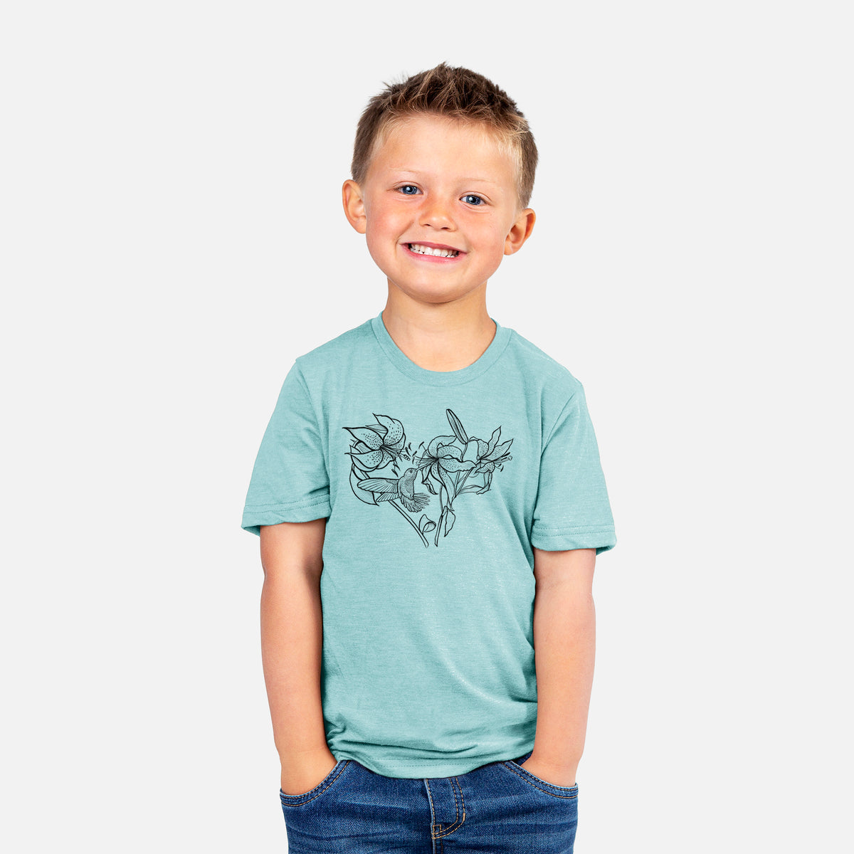 Smiling boy wearing a youth t-shirt printed with a black ink line drawing of lilies and a hummingbird arranged in a heart shape.