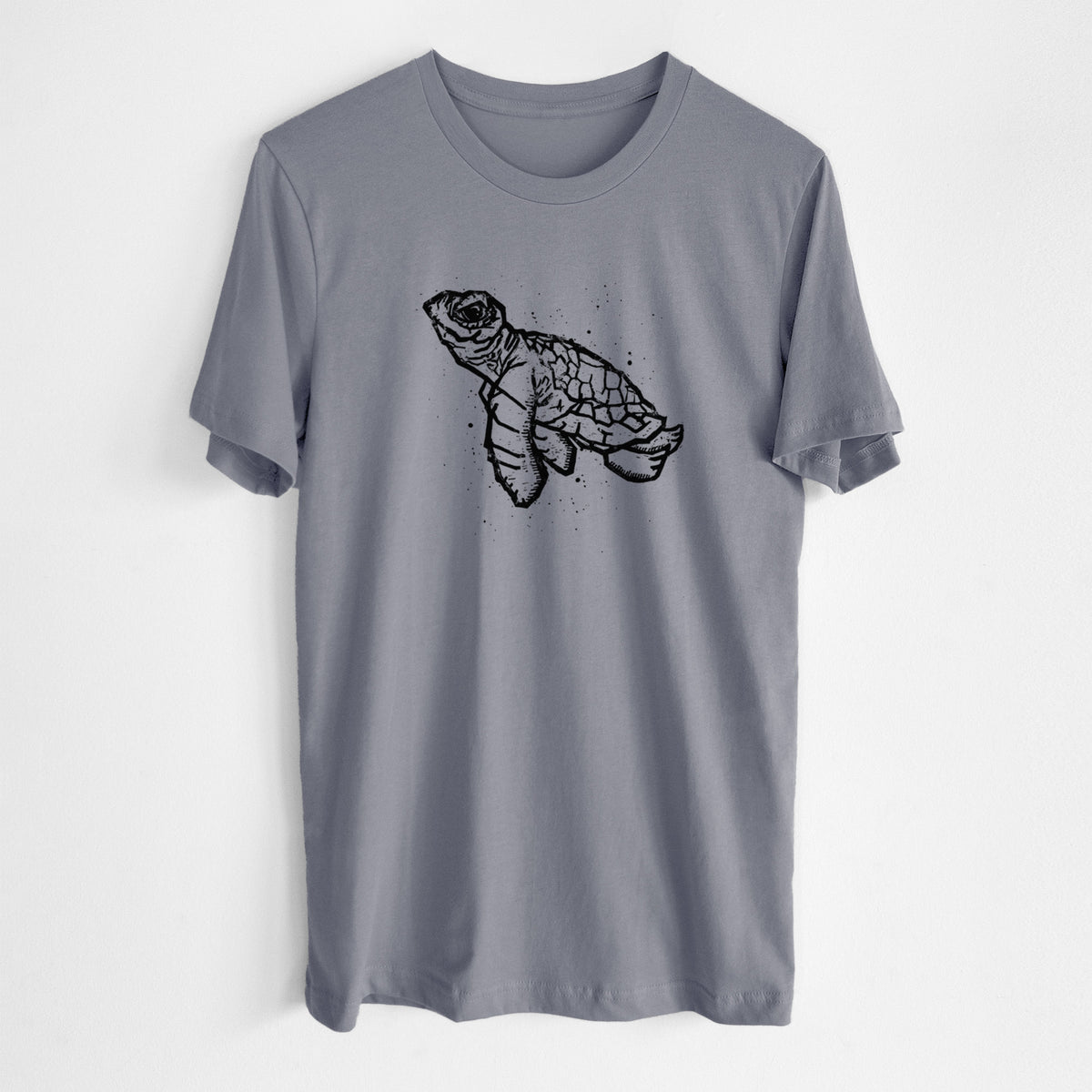 Storm grey lightweight cotton t-shirt laid flat, printed with a black linocut-style illustration of a baby sea turtle with a patterned shell and ink splatters.
