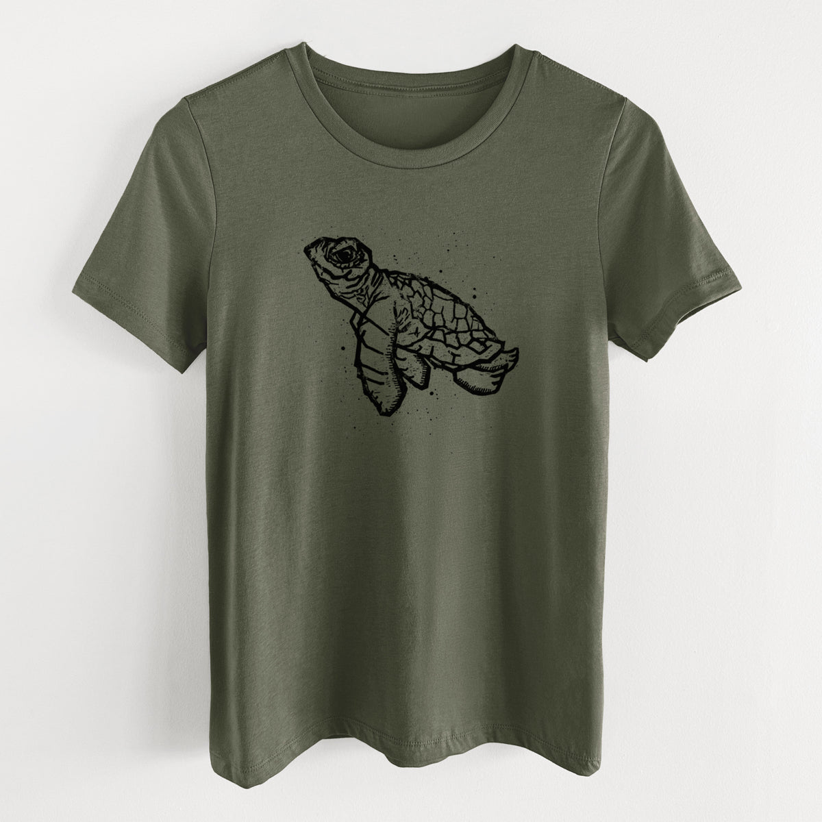 Military green women's relaxed fit cotton t-shirt laid flat, printed with a black linocut-style illustration of a baby sea turtle with a patterned shell and ink splatters.