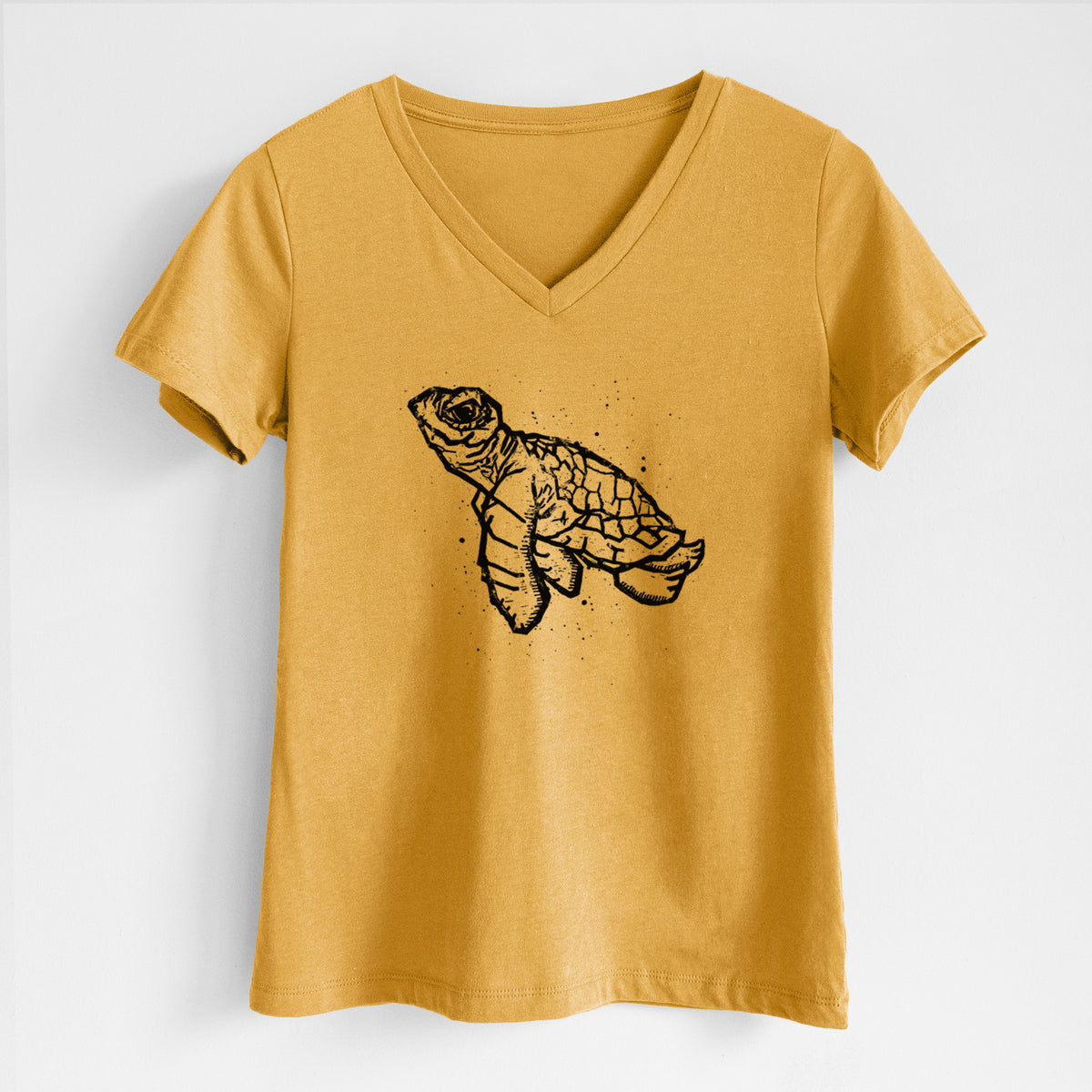 Honeycomb yellow women's relaxed fit cotton V-neck t-shirt laid flat, printed with a black linocut-style illustration of a baby sea turtle with a patterned shell and ink splatters.