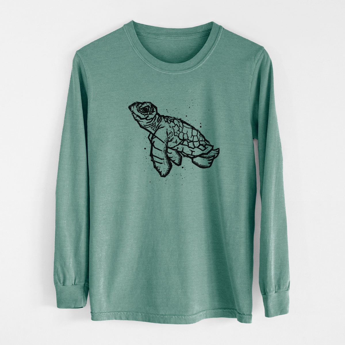 Pine green Comfort Colors long sleeve shirt laid flat, printed with a black linocut-style illustration of a baby sea turtle with a patterned shell and ink splatters.