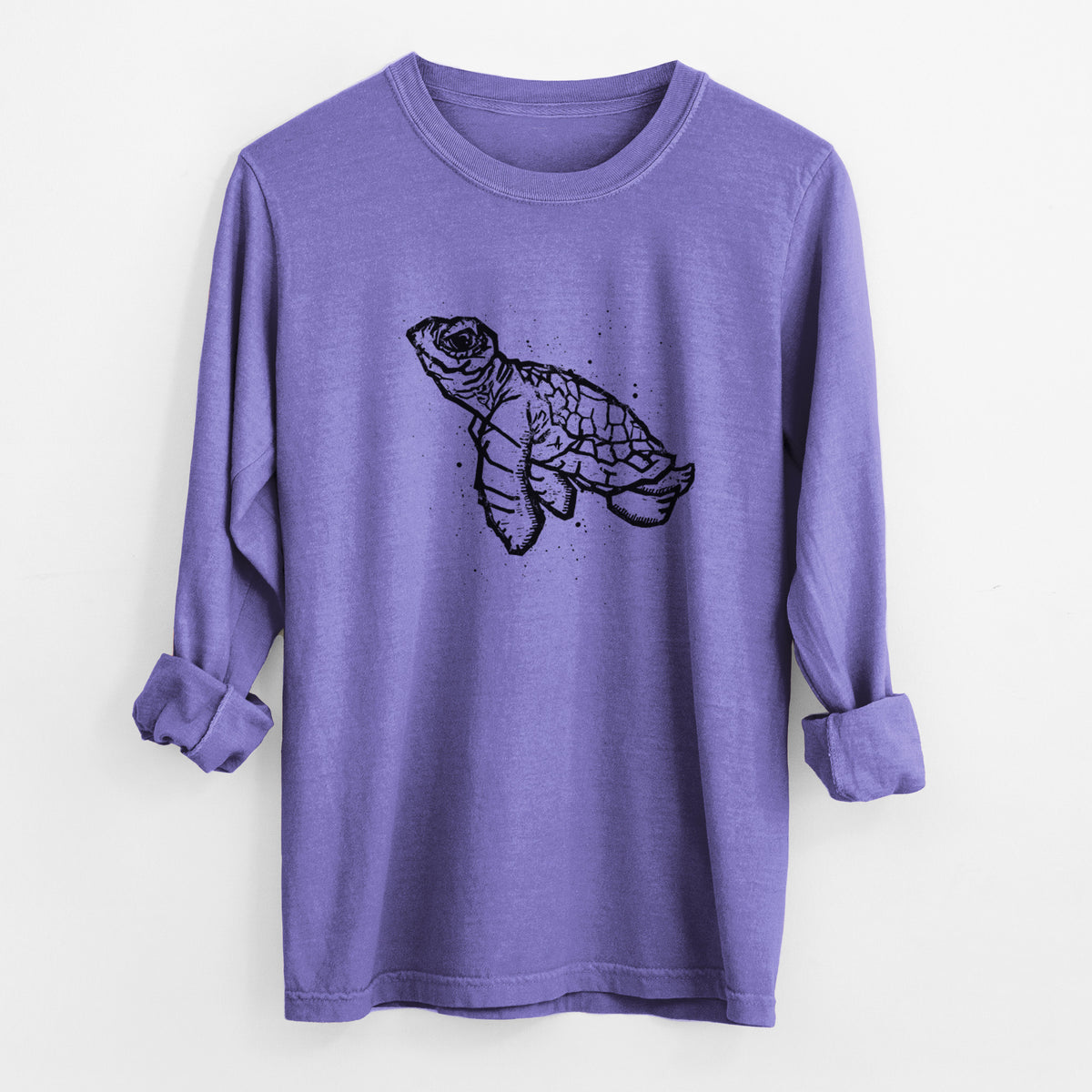 Violet purple Comfort Colors long sleeve shirt laid flat with the cuffs rolled, printed with a black linocut-style illustration of a baby sea turtle with a patterned shell and ink splatters.