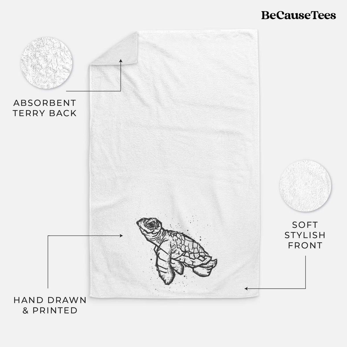 White hand towel printed with a black linocut-style illustration of a baby sea turtle with a patterned shell and ink splatters.