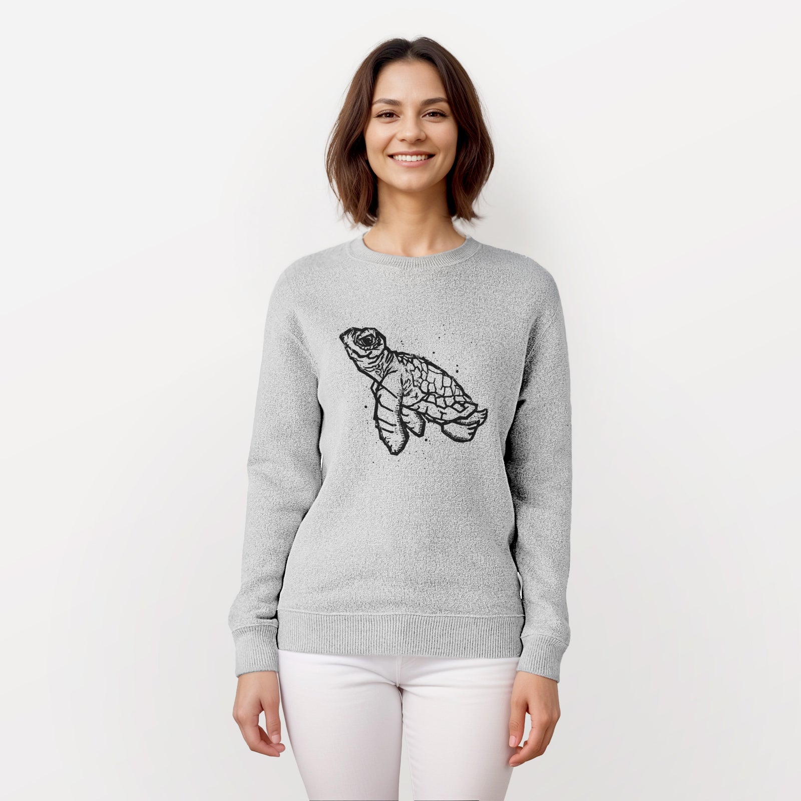 Salt and pepper knit sweatshirt laid flat, printed with a black linocut-style illustration of a baby sea turtle with a patterned shell and ink splatters.