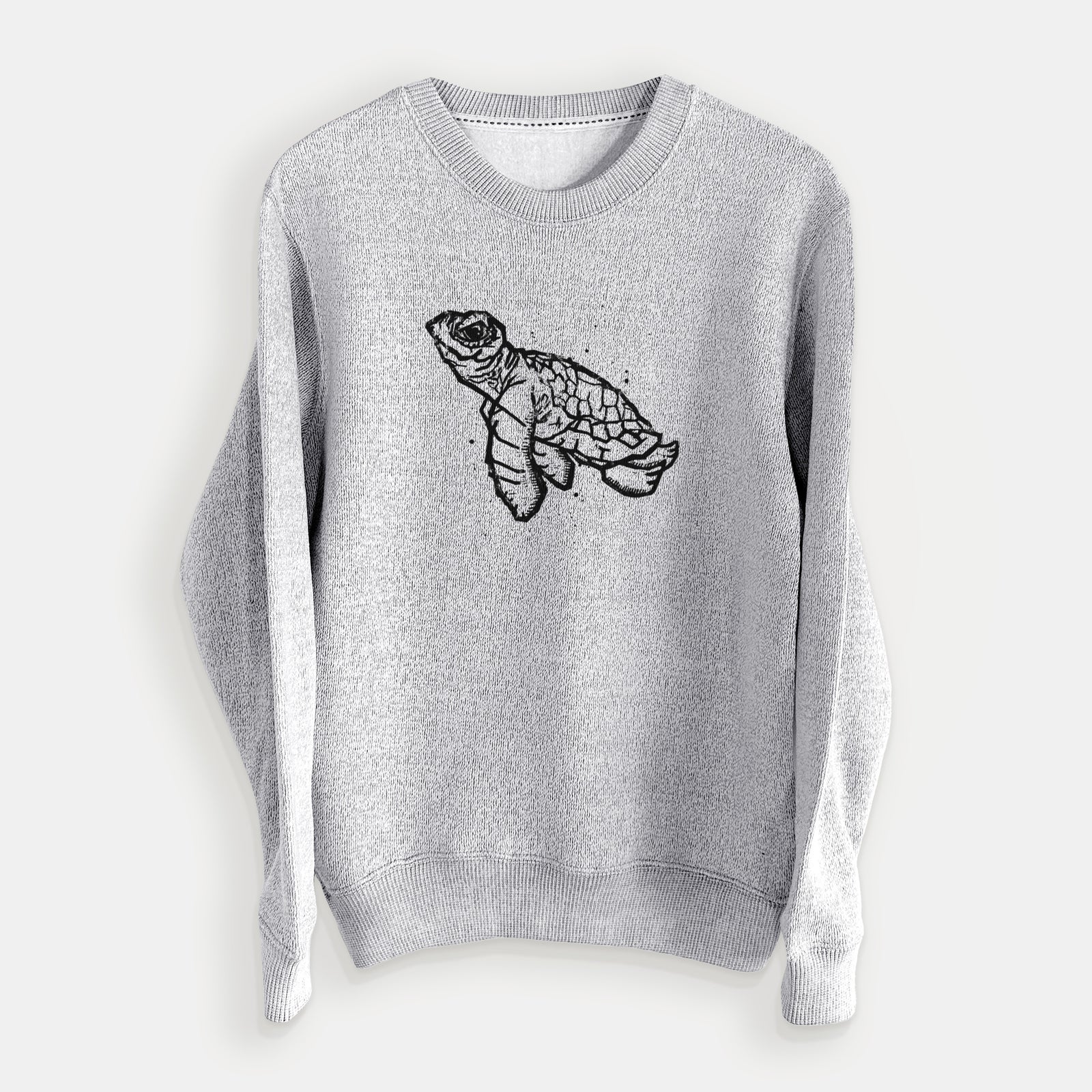 Salt and pepper knit sweatshirt laid flat, printed with a black linocut-style illustration of a baby sea turtle with a patterned shell and ink splatters.