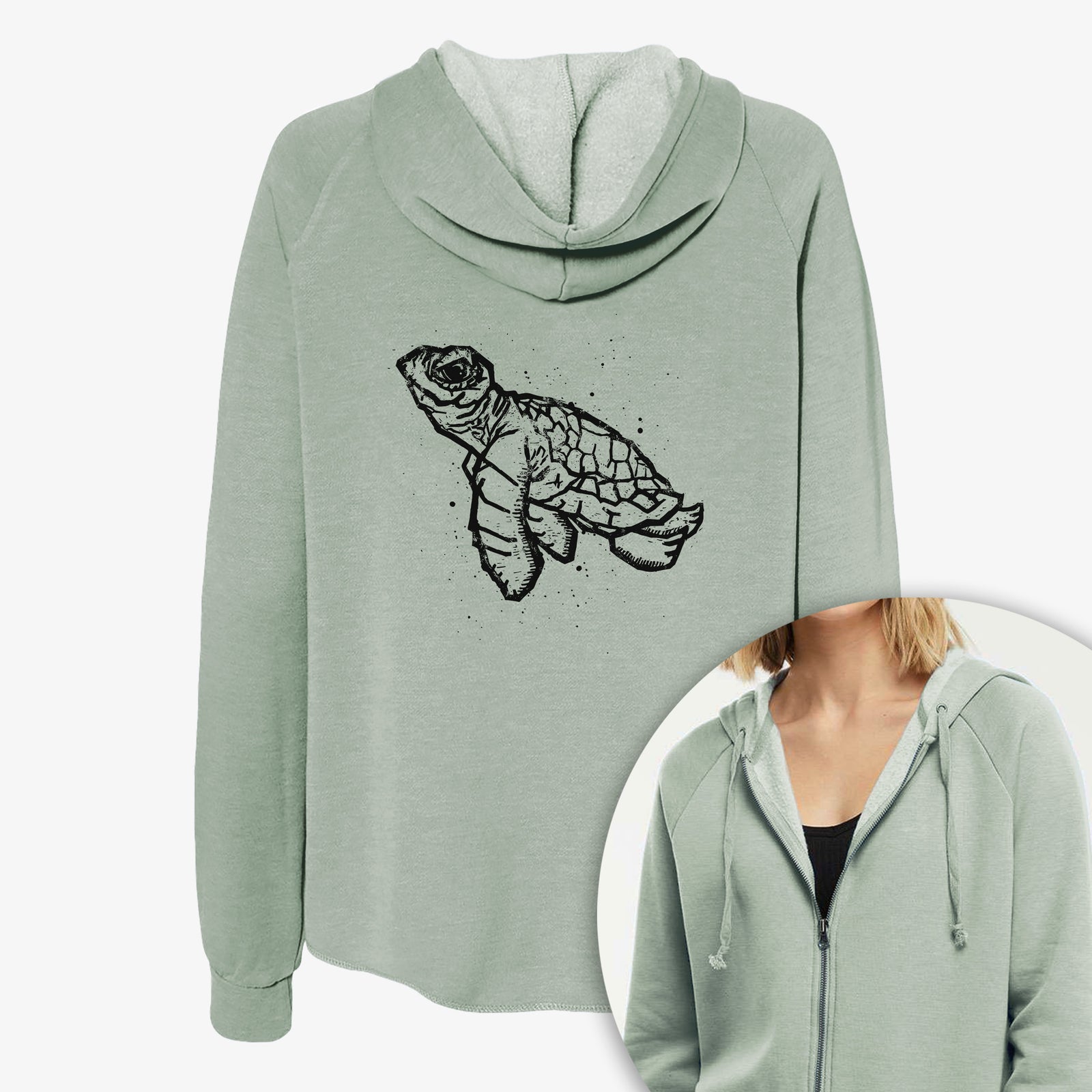 Women's Cali Wave zip-up sweatshirt printed with a black linocut-style illustration of a baby sea turtle with a patterned shell and ink splatters, with a close-up of the zipper.