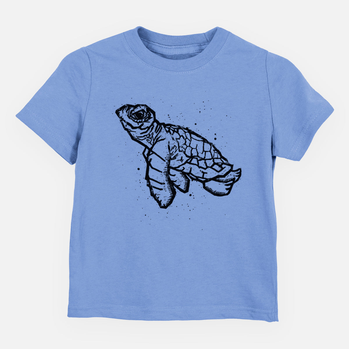 Carolina blue toddler t-shirt laid flat, printed with a black linocut-style illustration of a baby sea turtle with a patterned shell and ink splatters.