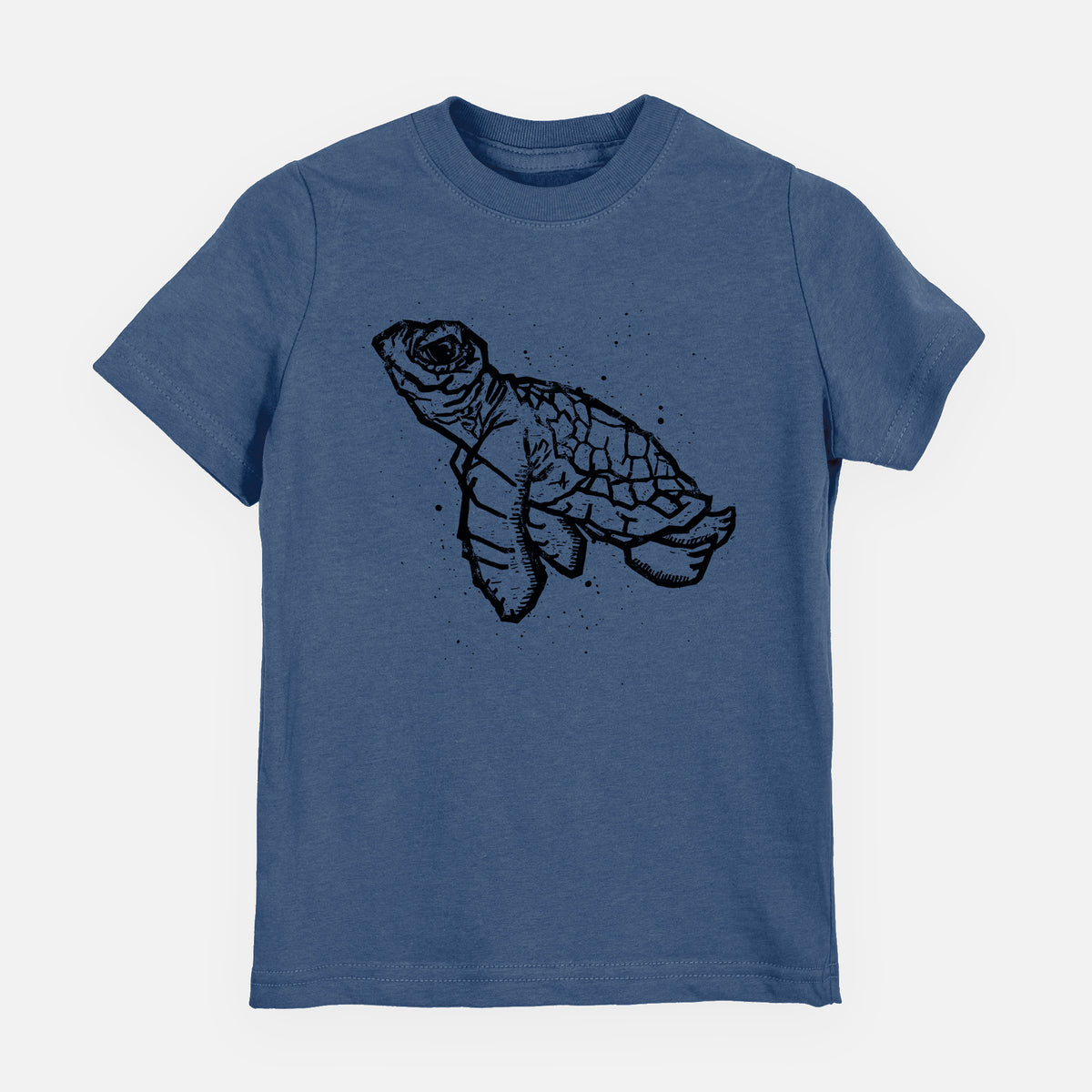 Indigo blue youth t-shirt laid flat, printed with a black linocut-style illustration of a baby sea turtle with a patterned shell and ink splatters.