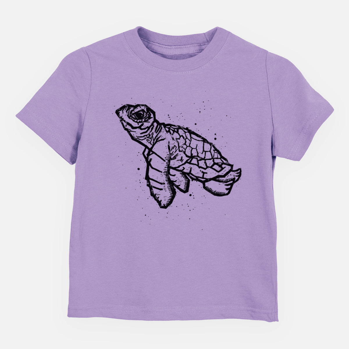 Lavender toddler t-shirt laid flat, printed with a black linocut-style illustration of a baby sea turtle with a patterned shell and ink splatters.