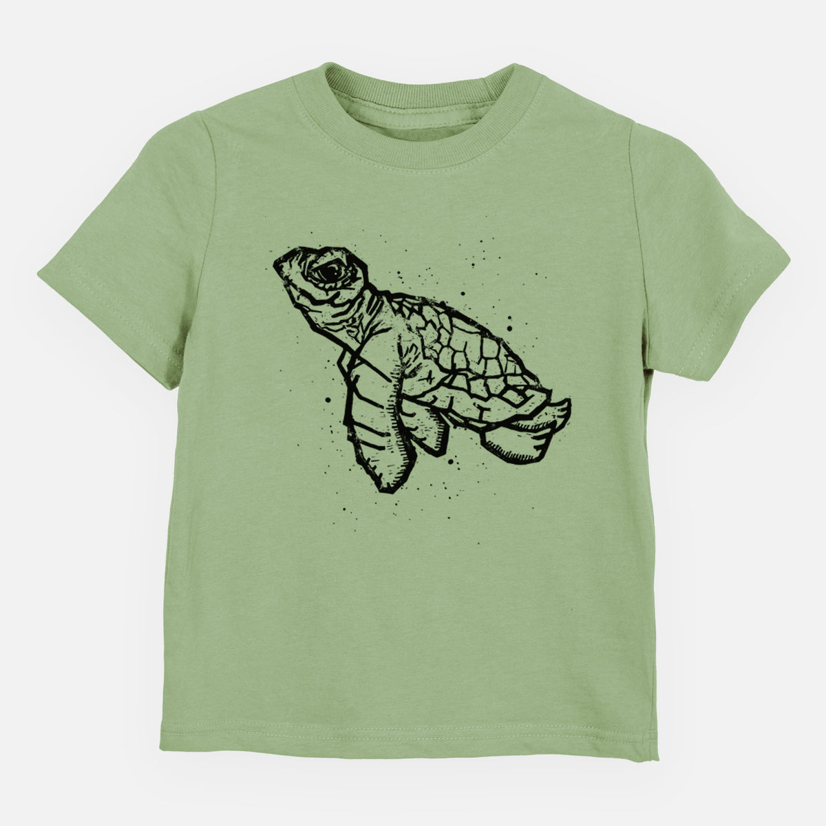 Sage green toddler t-shirt laid flat, printed with a black linocut-style illustration of a baby sea turtle with a patterned shell and ink splatters.