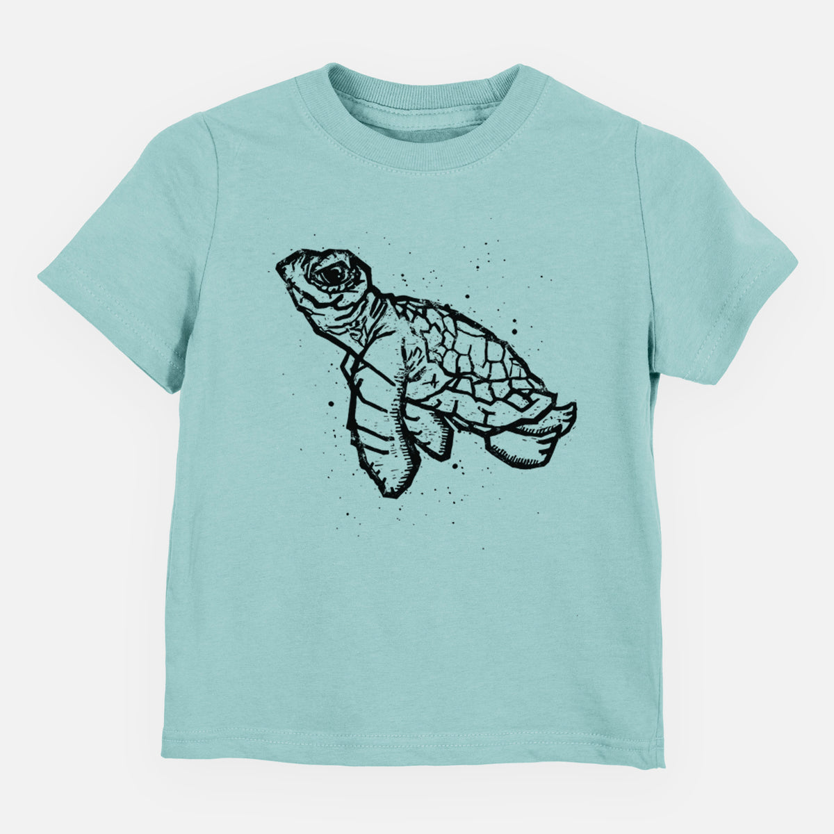 Saltwater toddler t-shirt laid flat, printed with a black linocut-style illustration of a baby sea turtle with a patterned shell and ink splatters.