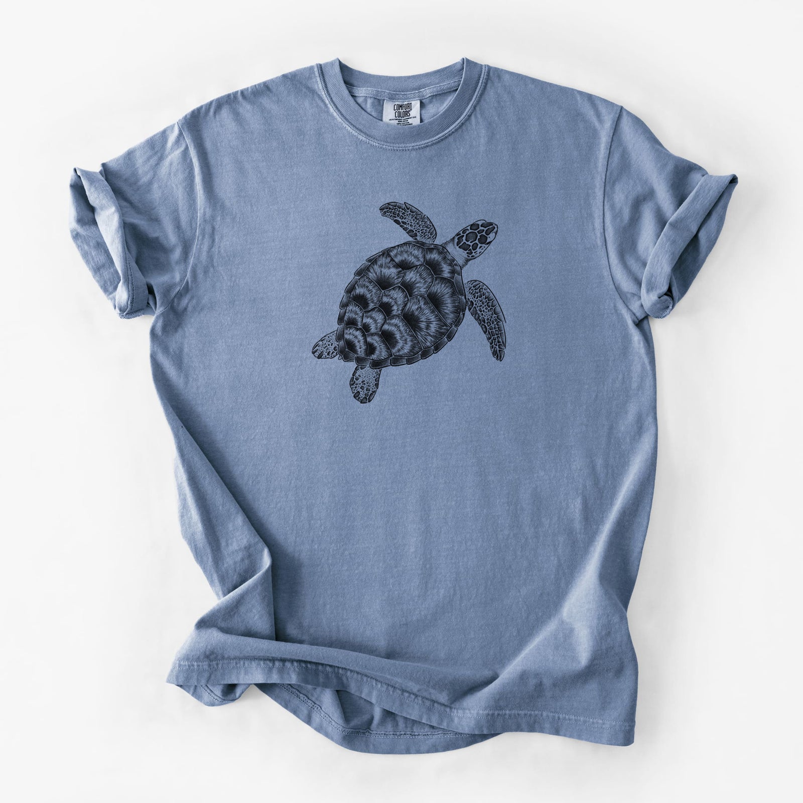 Blue jean Comfort Colors t-shirt laid flat, printed with a detailed black ink illustration of a loggerhead sea turtle swimming, seen from above.