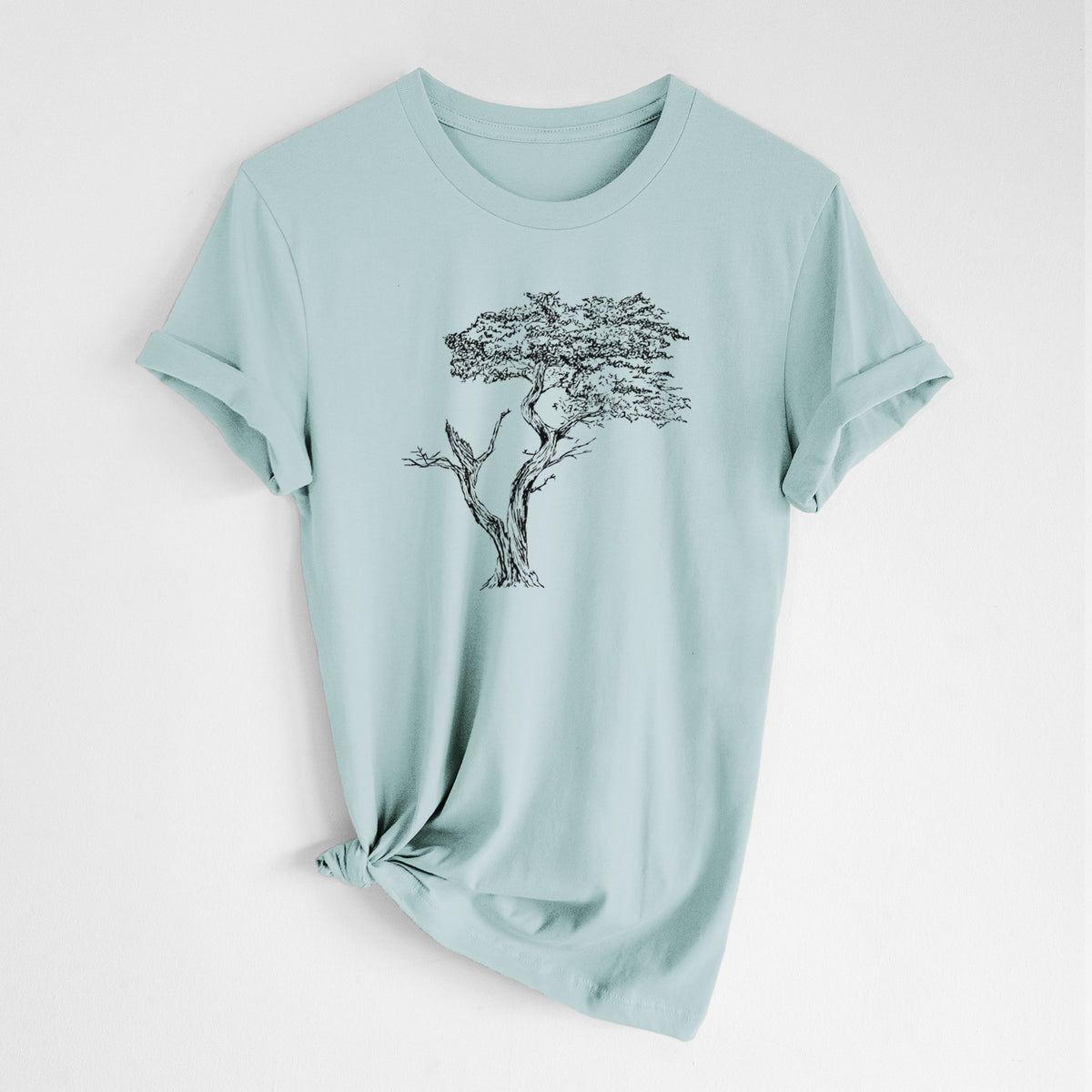 Dusty blue lightweight cotton t-shirt laid flat with the sleeves rolled, printed with a black ink illustration of the windswept Lone Cypress tree on a rocky outcrop.