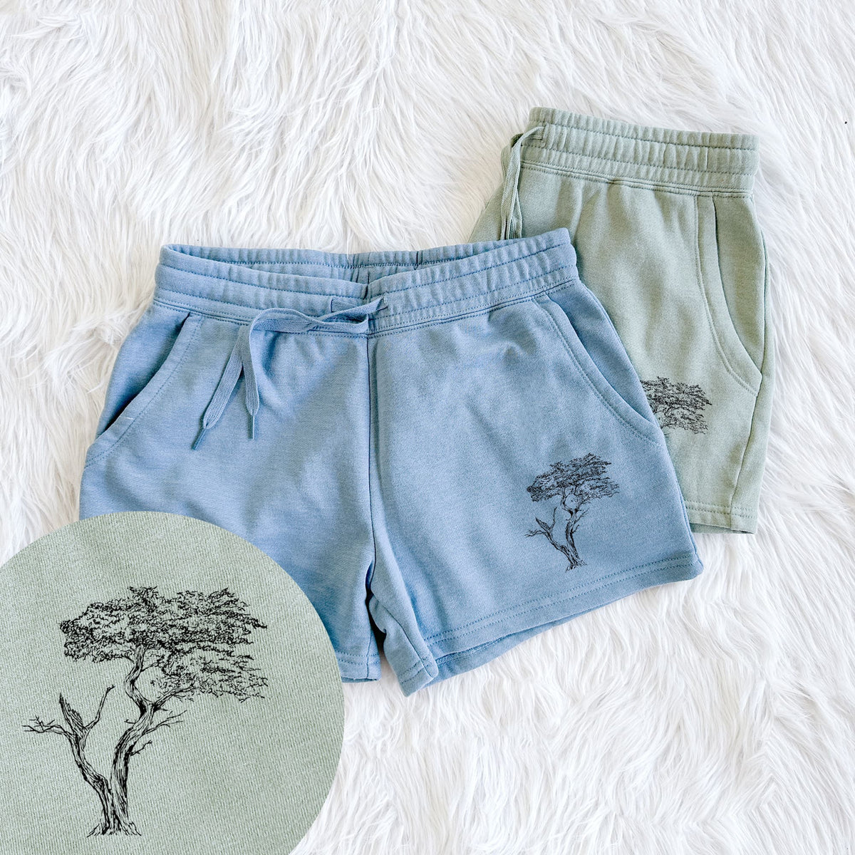 Two pairs of Cali Wave shorts in different colors printed with a black ink illustration of the windswept Lone Cypress tree on a rocky outcrop, with a close-up of the print.