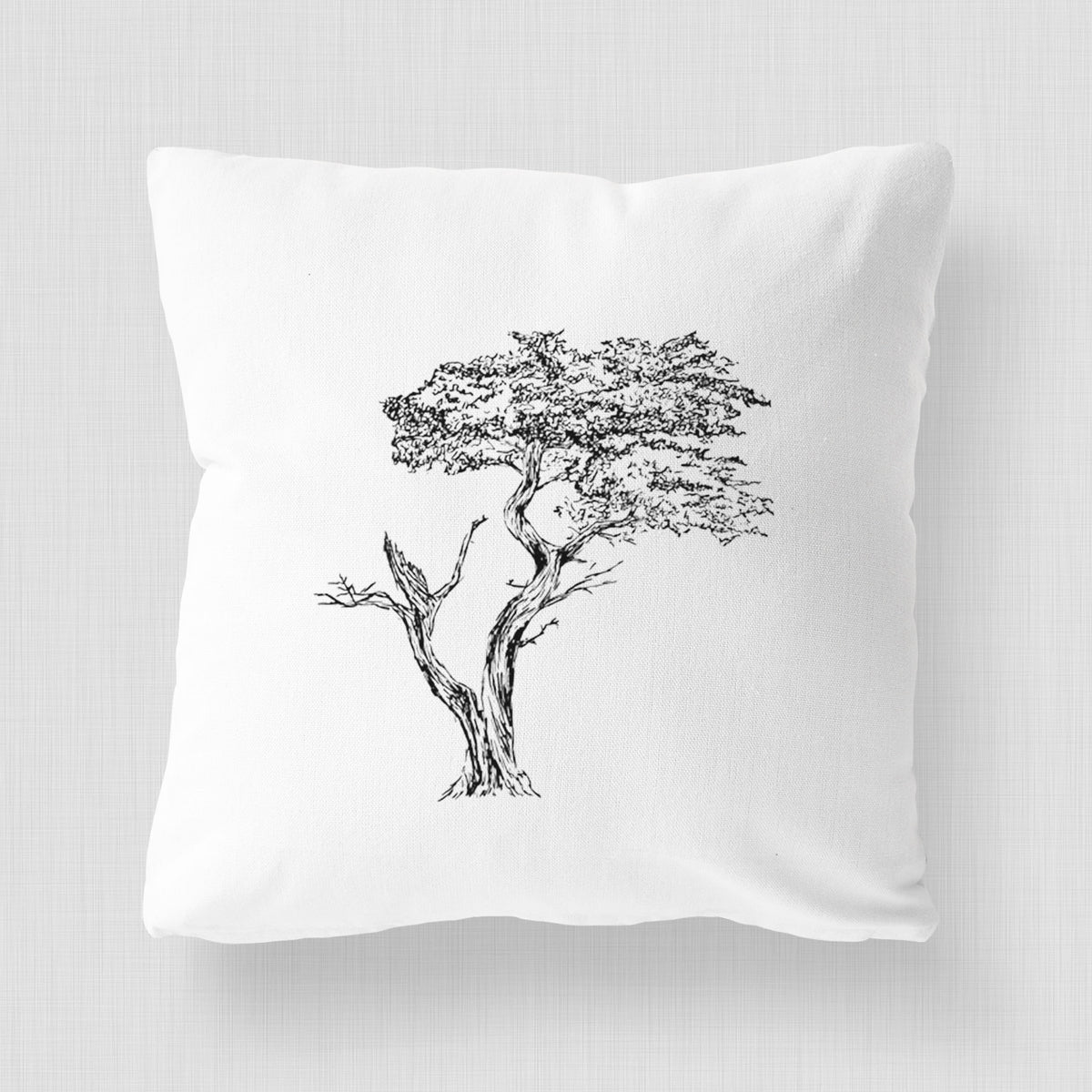 White pillow cover printed with a black ink illustration of the windswept Lone Cypress tree on a rocky outcrop.