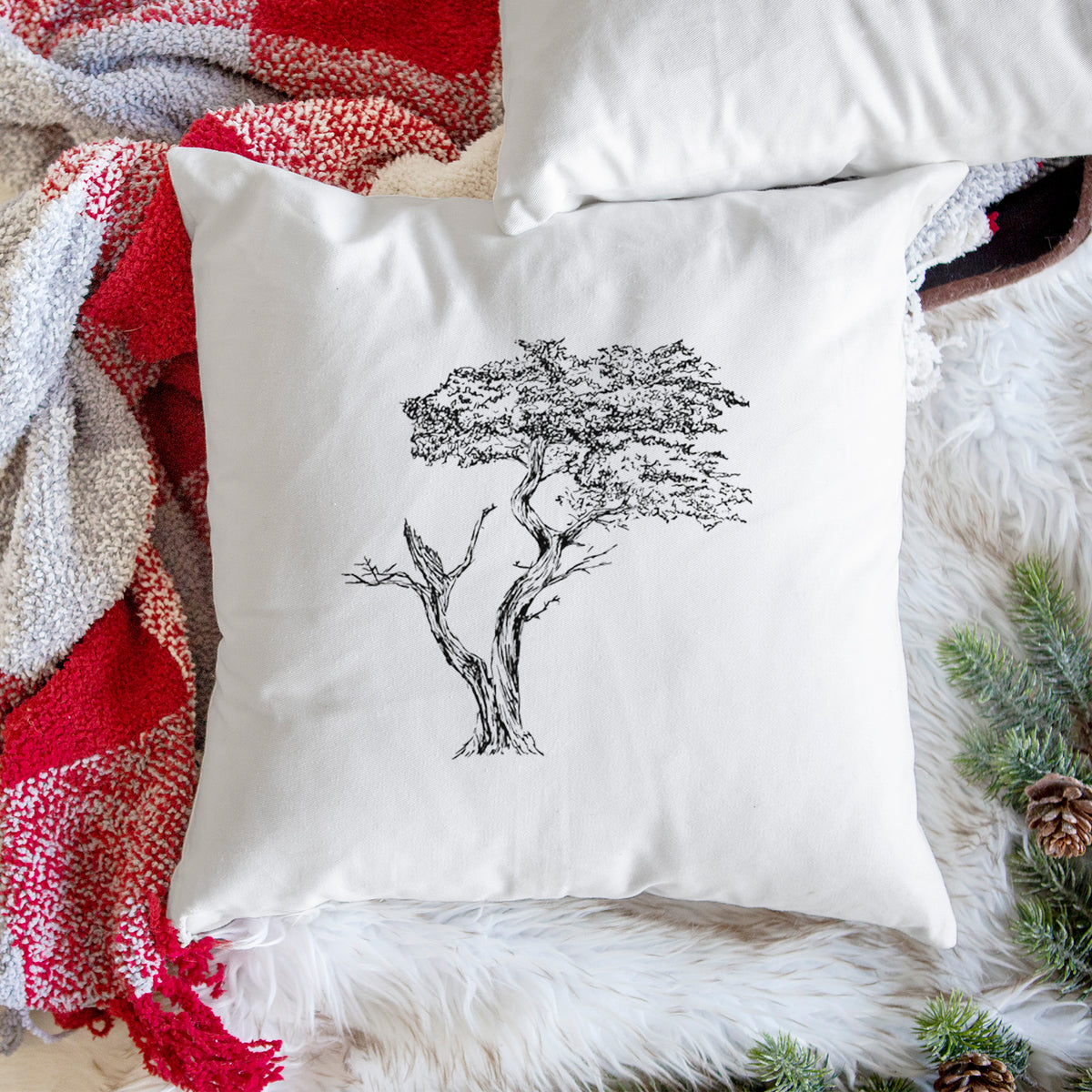 White pillow cover printed with a black ink illustration of the windswept Lone Cypress tree on a rocky outcrop, on a woven chair.