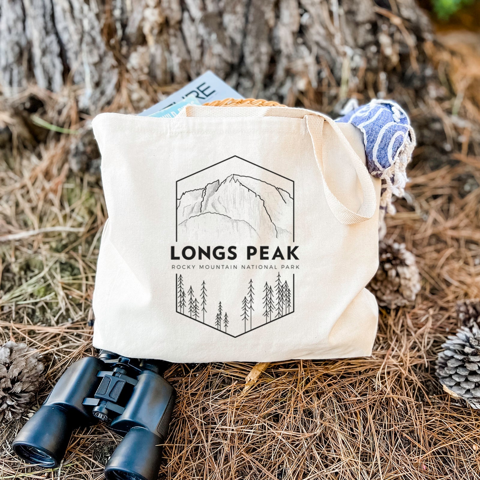 Natural canvas tote bag printed with a black line art badge of Longs Peak above a pine forest, with the words Longs Peak, Rocky Mountain National Park.