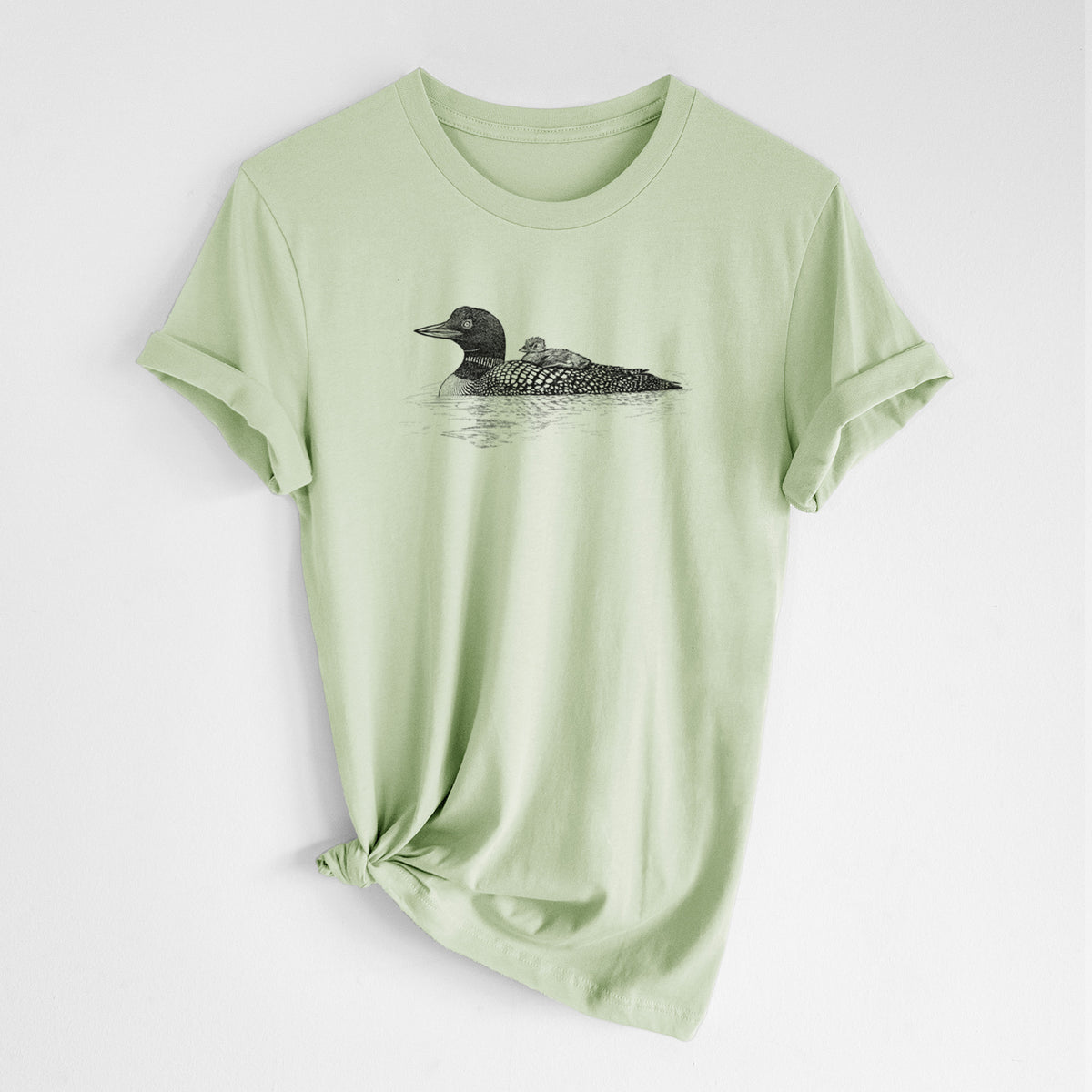 Spring green lightweight cotton t-shirt laid flat with the sleeves rolled, printed with a black ink sketch of a common loon floating on water with a chick riding on its back.