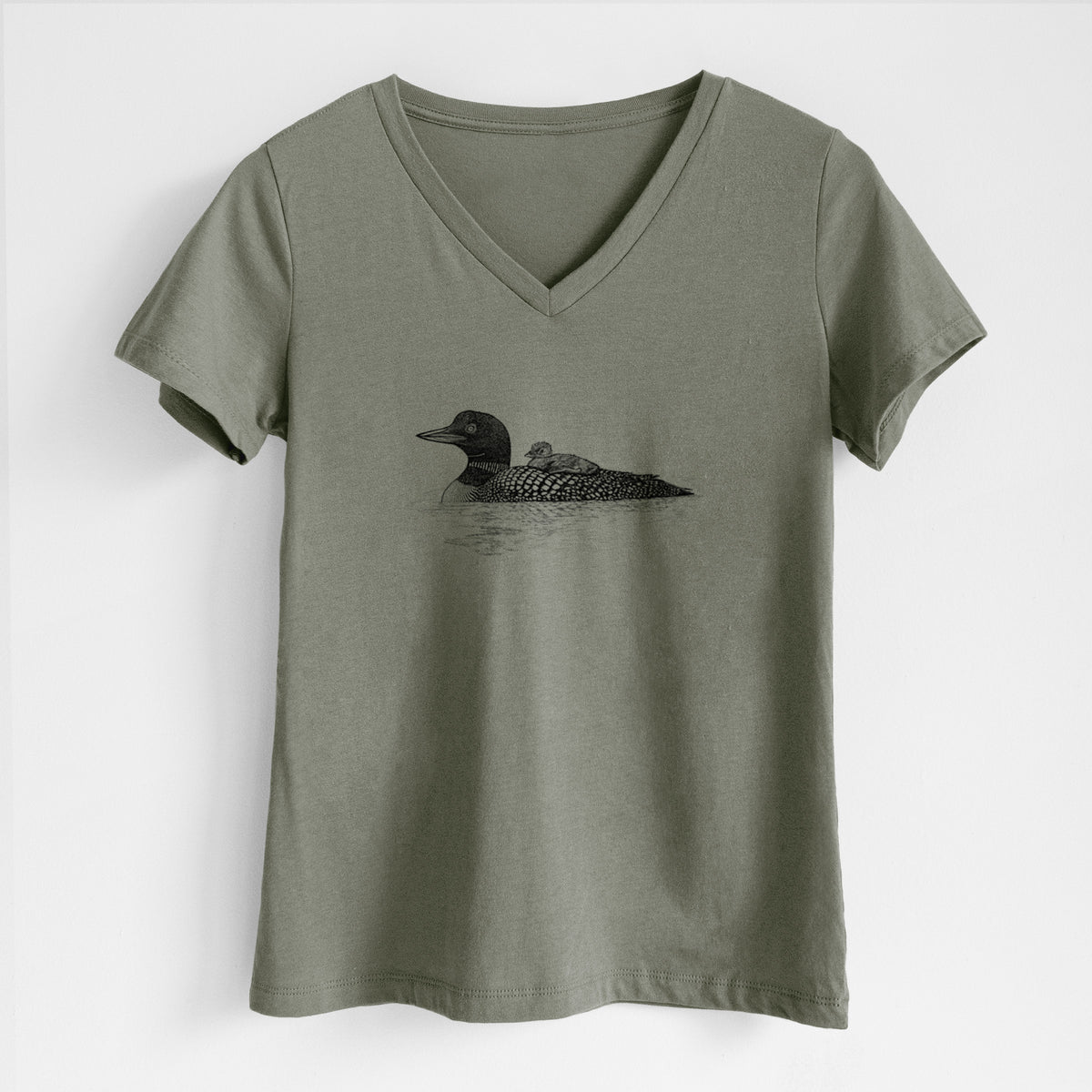 Military green women's relaxed fit cotton V-neck t-shirt laid flat, printed with a black ink sketch of a common loon floating on water with a chick riding on its back.