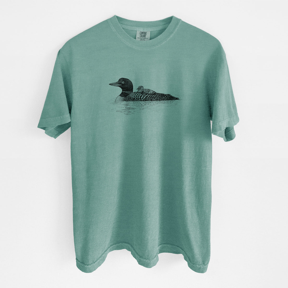 Reef green Comfort Colors t-shirt laid flat, printed with a black ink sketch of a common loon floating on water with a chick riding on its back.
