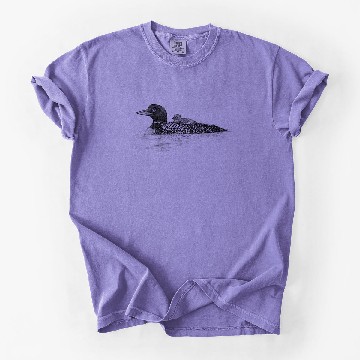 Violet purple Comfort Colors t-shirt laid flat, printed with a black ink sketch of a common loon floating on water with a chick riding on its back.