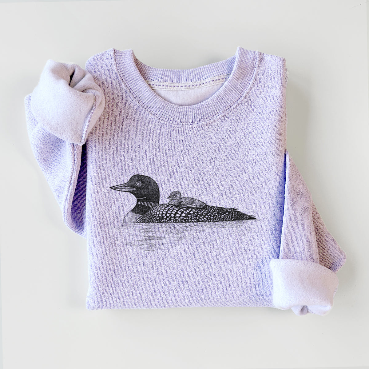 Ice purple knit sweatshirt printed with a black ink sketch of a common loon floating on water with a chick riding on its back, styled flat.