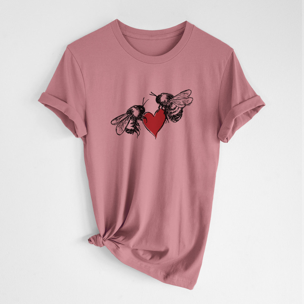 Mauve pink lightweight cotton t-shirt laid flat with the sleeves rolled, printed with a black ink illustration of two bees facing each other with a red heart between them.