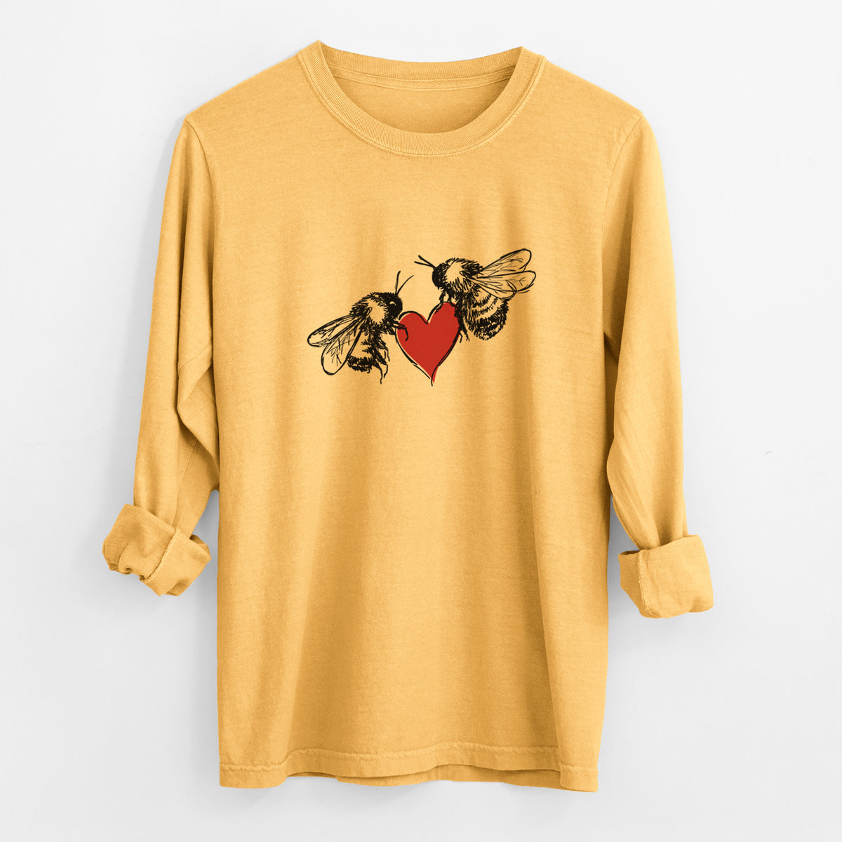 Golden wheat yellow Comfort Colors long sleeve shirt laid flat with the cuffs rolled, printed with a black ink illustration of two bees facing each other with a red heart between them.