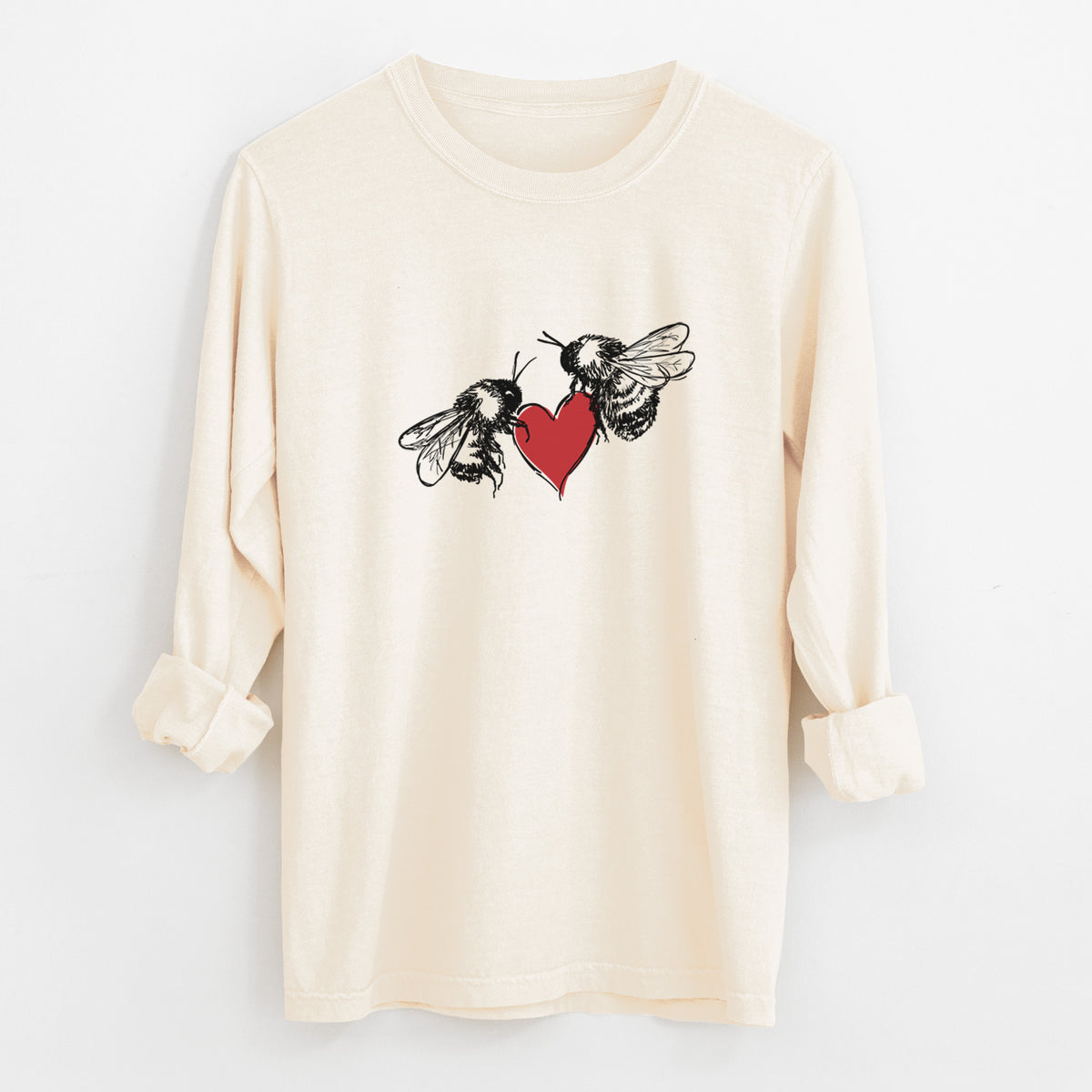Ivory Comfort Colors long sleeve shirt laid flat with the cuffs rolled, printed with a black ink illustration of two bees facing each other with a red heart between them.