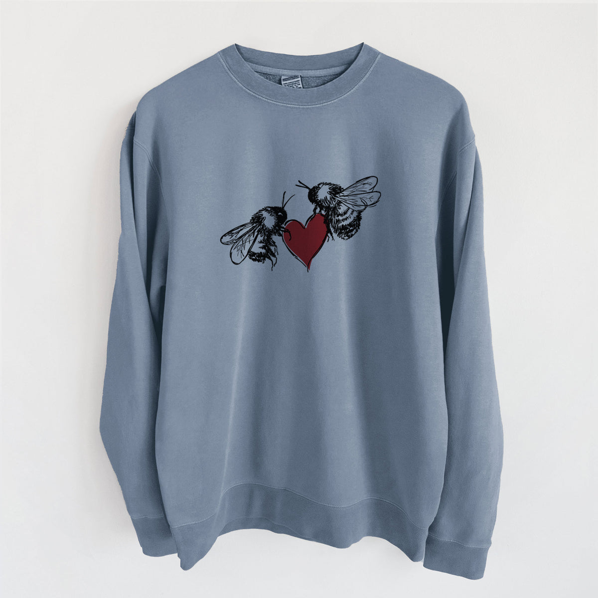 Slate blue pigment dyed crewneck sweatshirt laid flat, printed with a black ink illustration of two bees facing each other with a red heart between them.