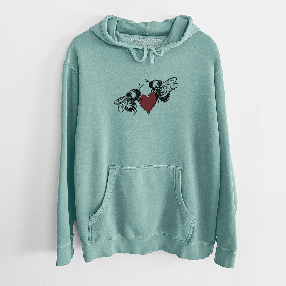Mint green pigment dyed hoodie laid flat, printed with a black ink illustration of two bees facing each other with a red heart between them.
