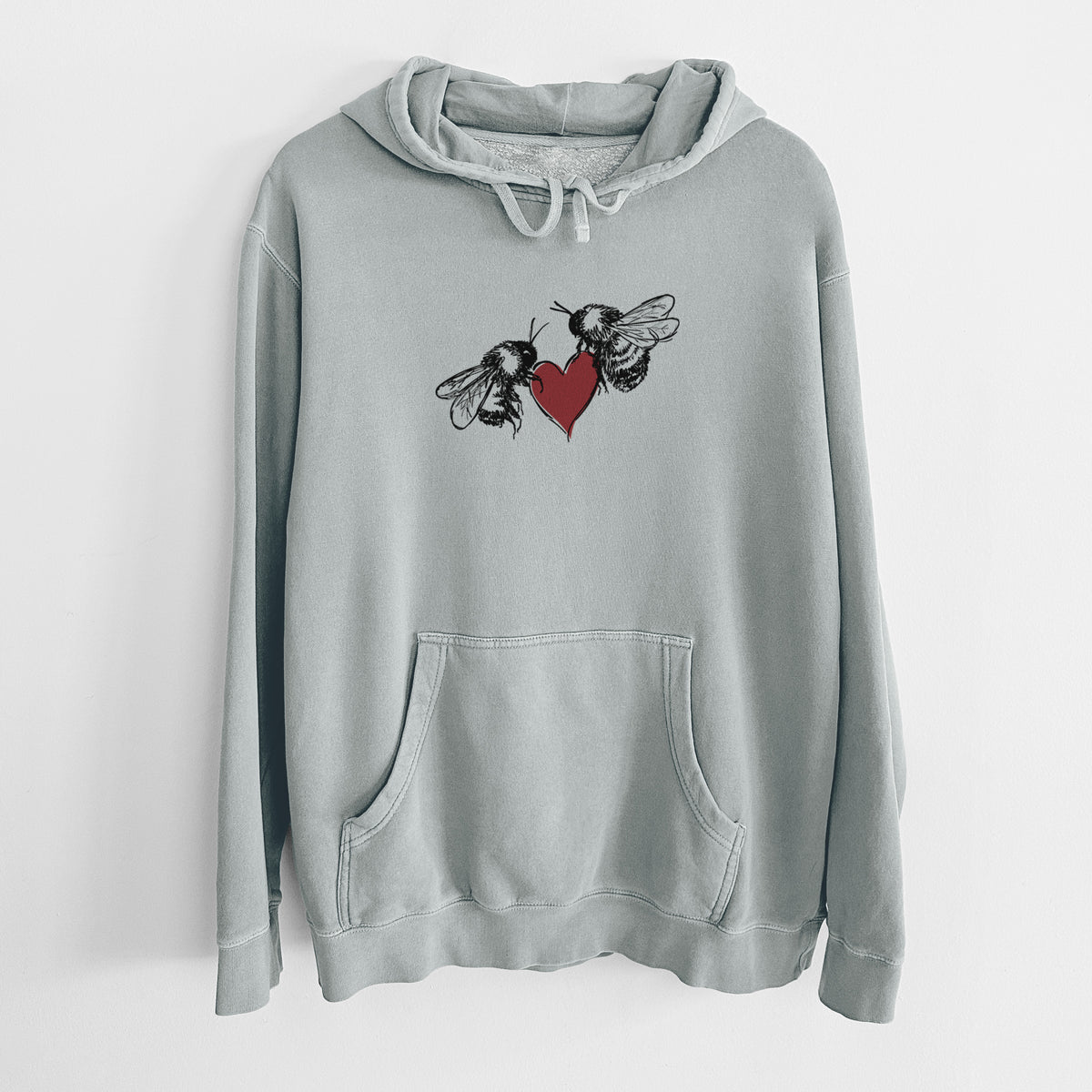 Sage green pigment dyed hoodie laid flat, printed with a black ink illustration of two bees facing each other with a red heart between them.