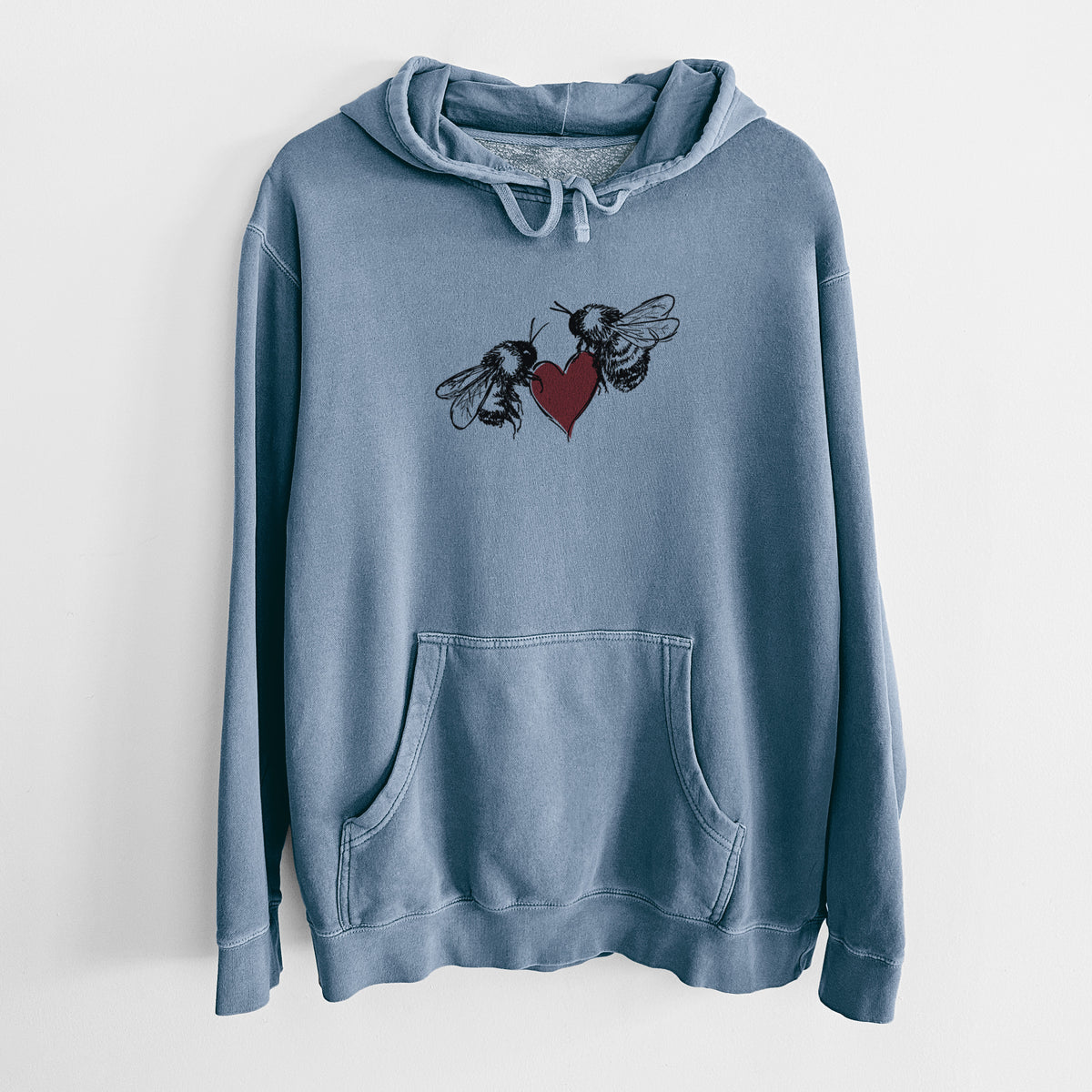 Slate blue pigment dyed hoodie laid flat, printed with a black ink illustration of two bees facing each other with a red heart between them.