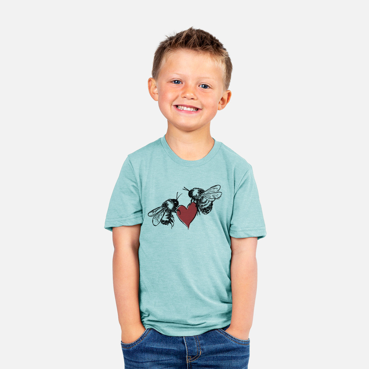 Smiling boy wearing a youth t-shirt printed with a black ink illustration of two bees facing each other with a red heart between them.