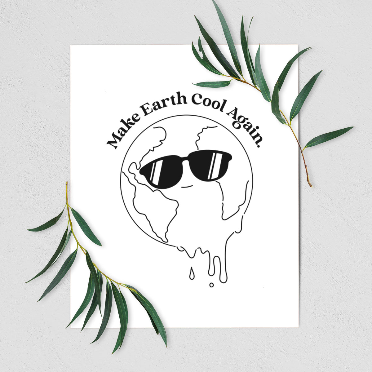 Art print of a melting Earth wearing black sunglasses, with the words Make Earth Cool Again, shown with eucalyptus leaves.