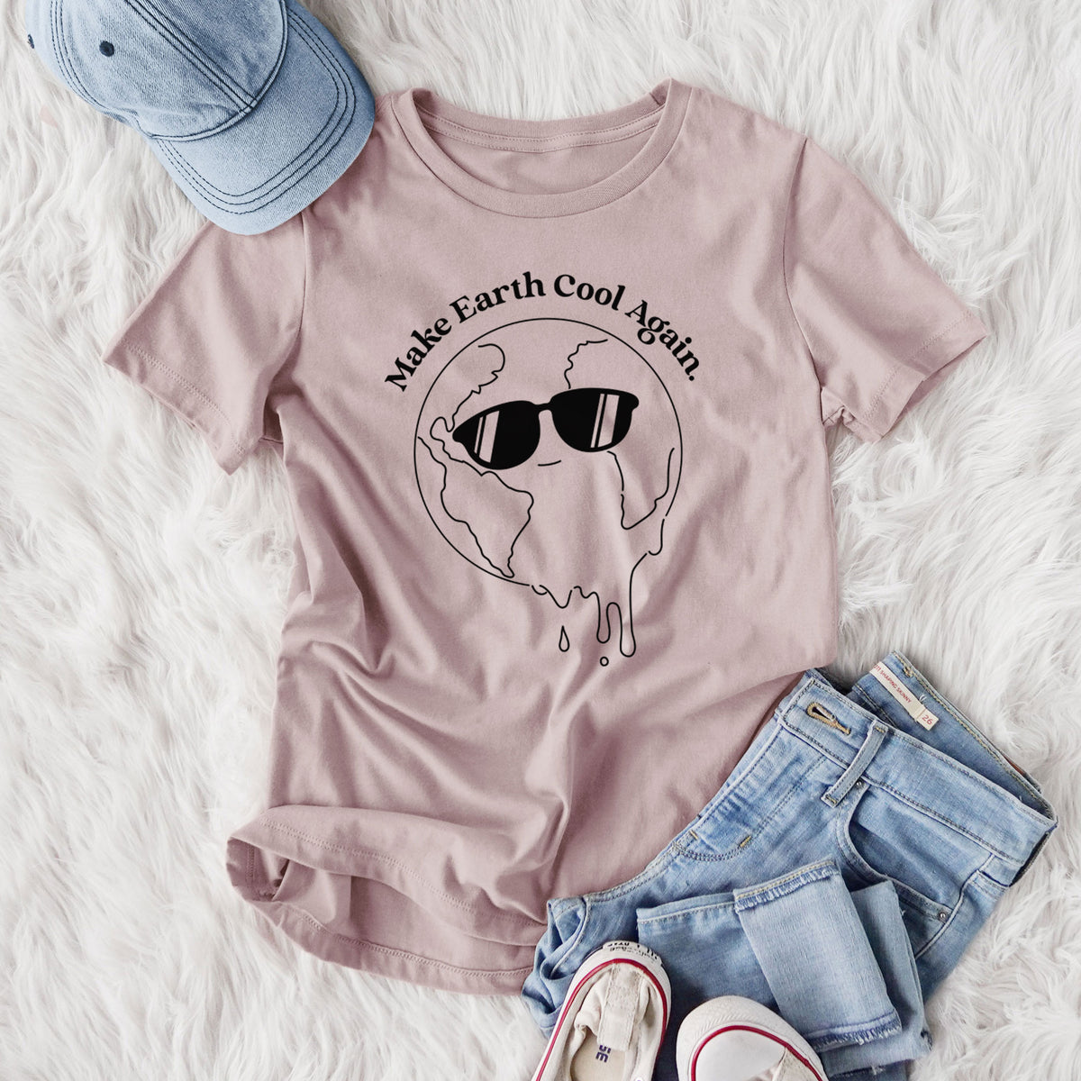 Women's relaxed fit cotton t-shirt printed with a melting Earth wearing black sunglasses, with the words Make Earth Cool Again, styled flat on a white faux fur rug with jeans.