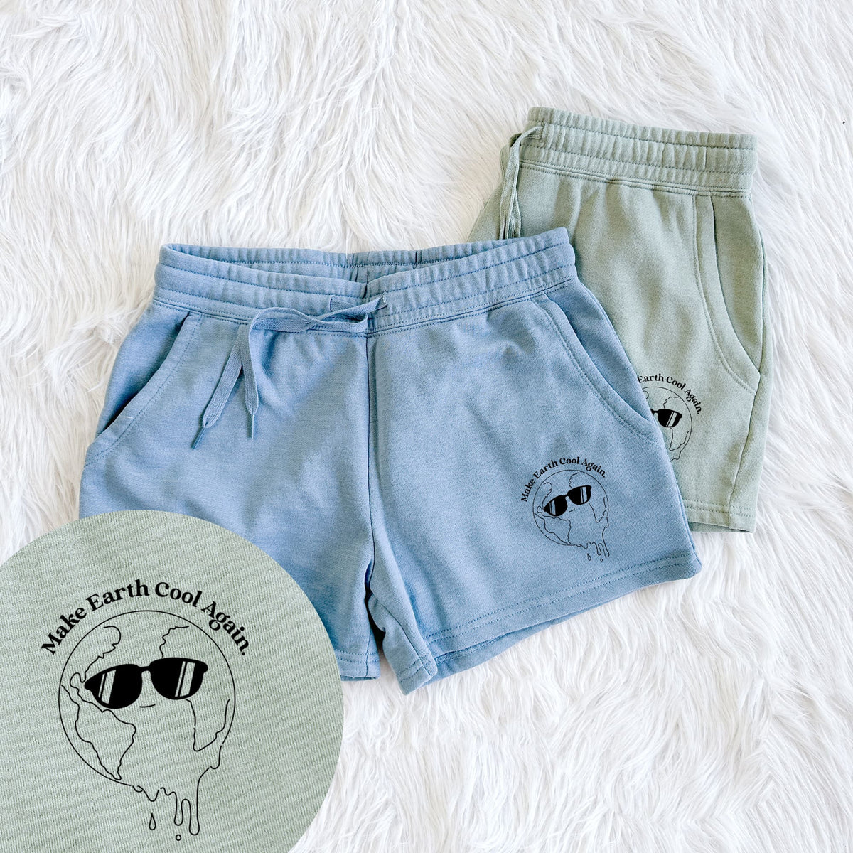 Two pairs of Cali Wave shorts in different colors printed with a melting Earth wearing black sunglasses, with the words Make Earth Cool Again, with a close-up of the print.