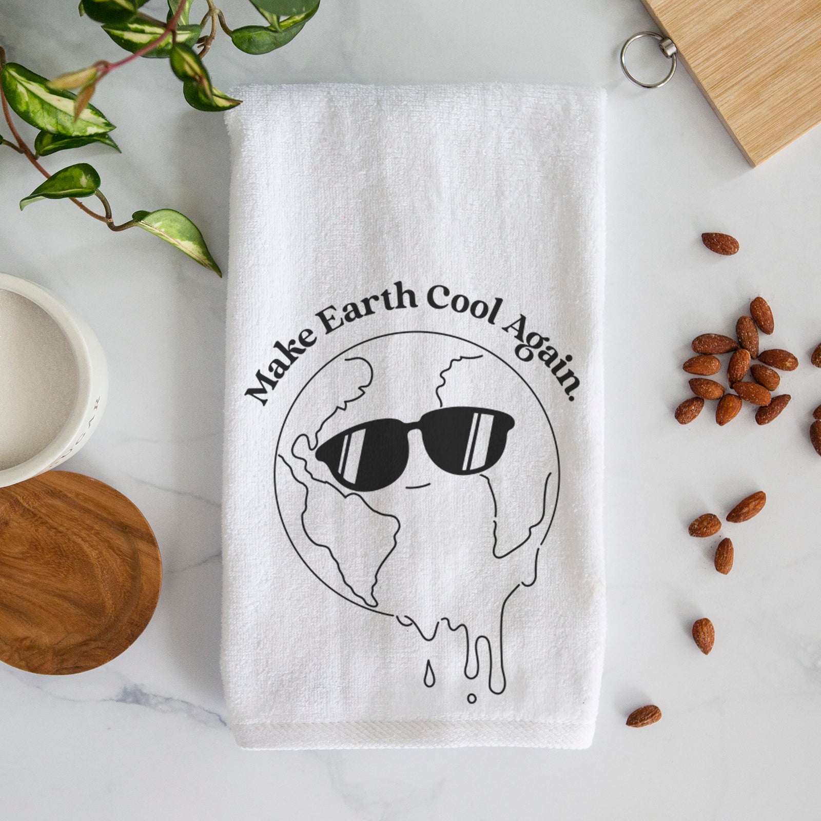 White hand towel printed with a melting Earth wearing black sunglasses, with the words Make Earth Cool Again.