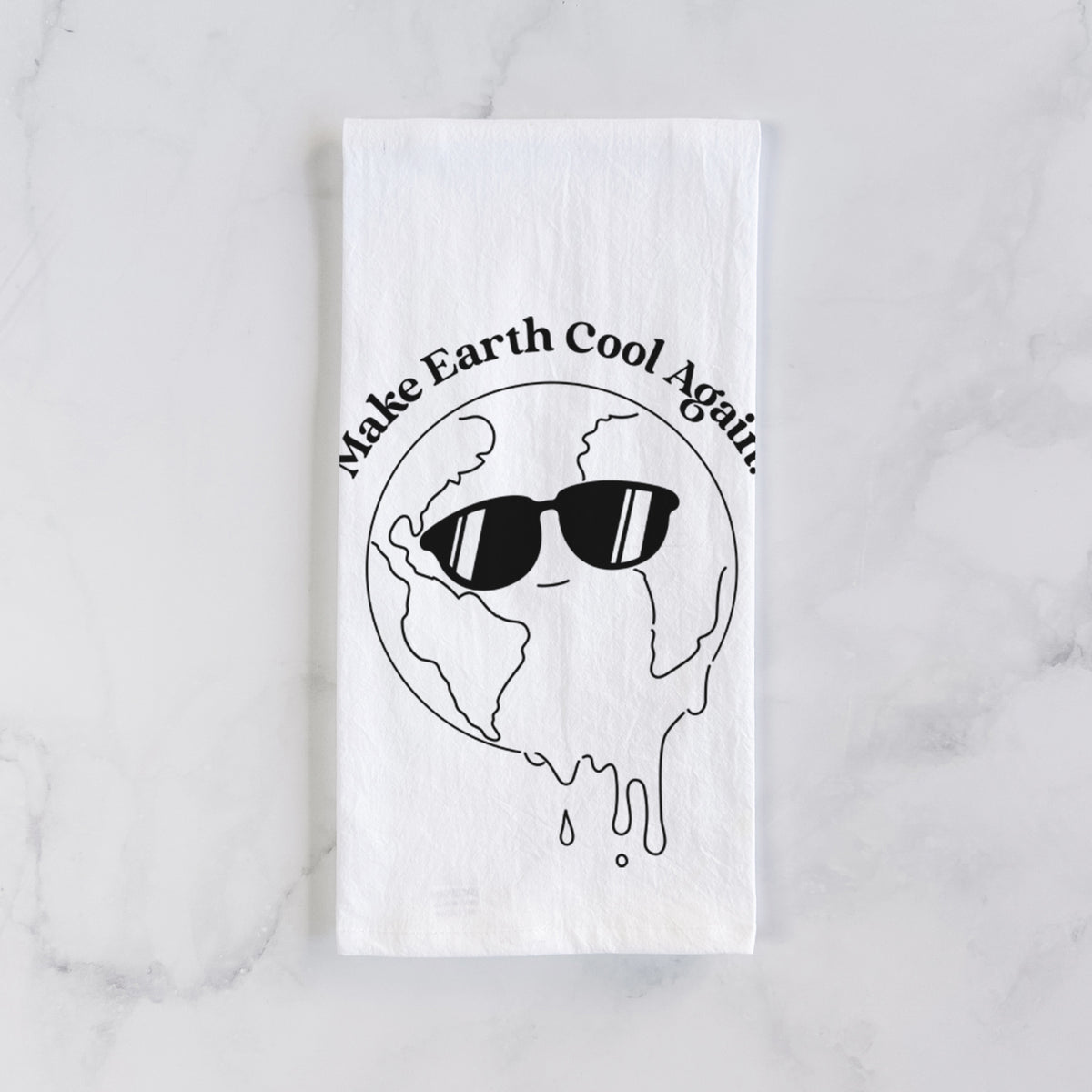 White cotton tea towel laid flat on marble, printed with a melting Earth wearing black sunglasses, with the words Make Earth Cool Again.