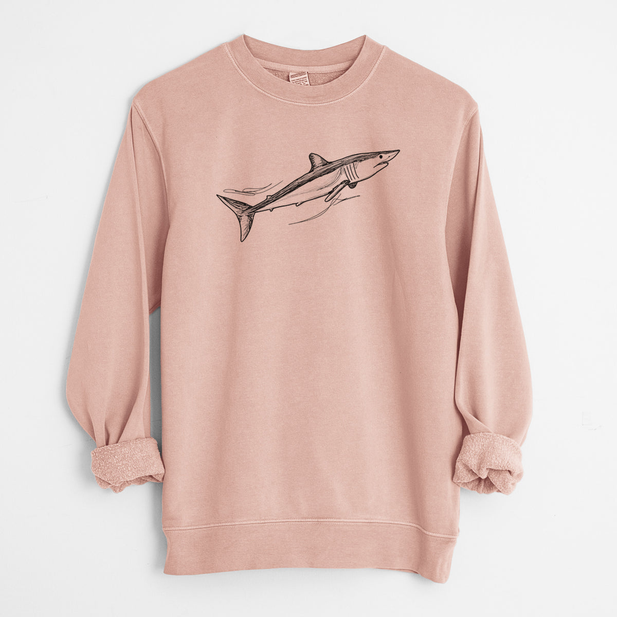Dusty pink pigment dyed crewneck sweatshirt laid flat with the sleeves rolled, printed with a black ink illustration of a mako shark swimming.