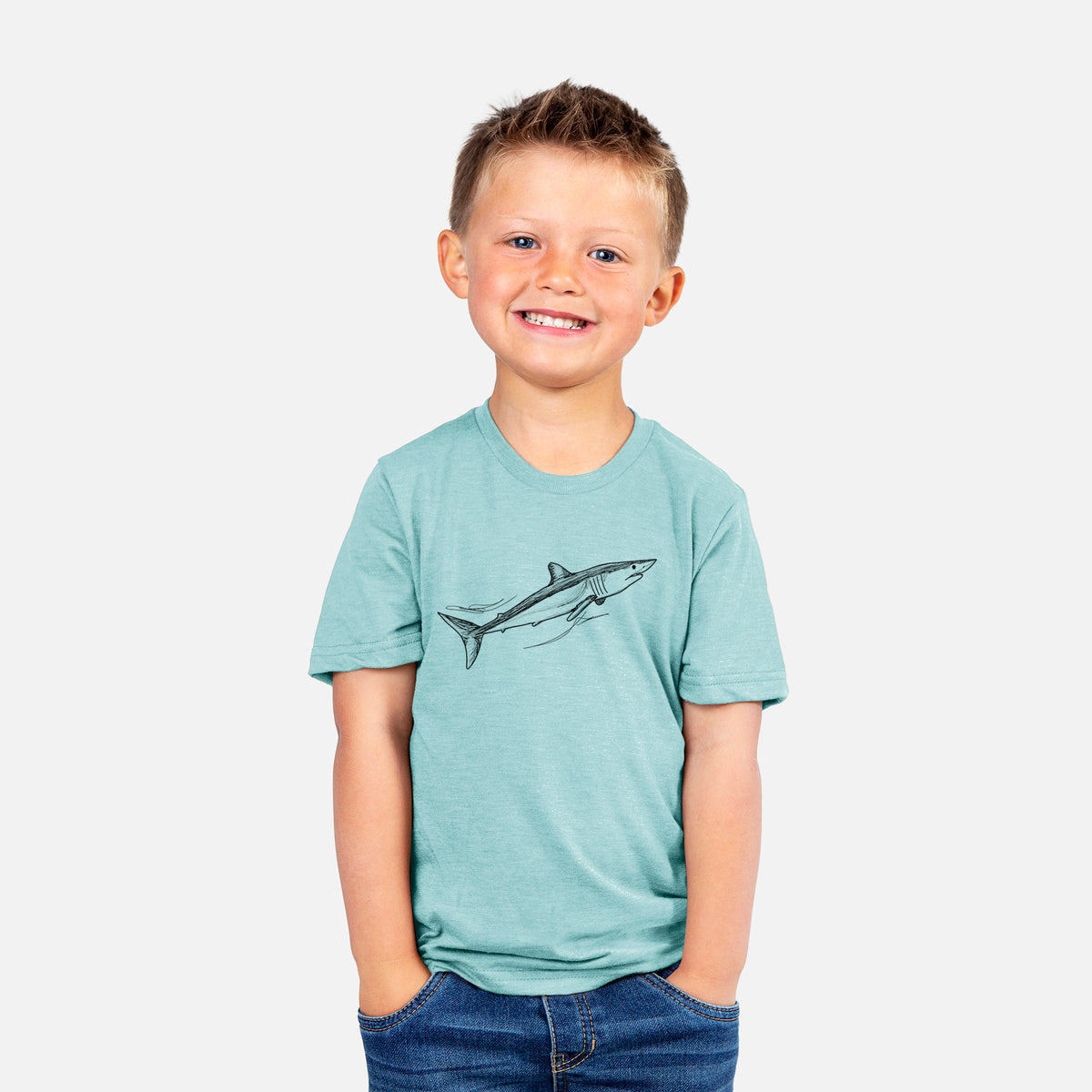 Smiling boy wearing a youth t-shirt printed with a black ink illustration of a mako shark swimming.