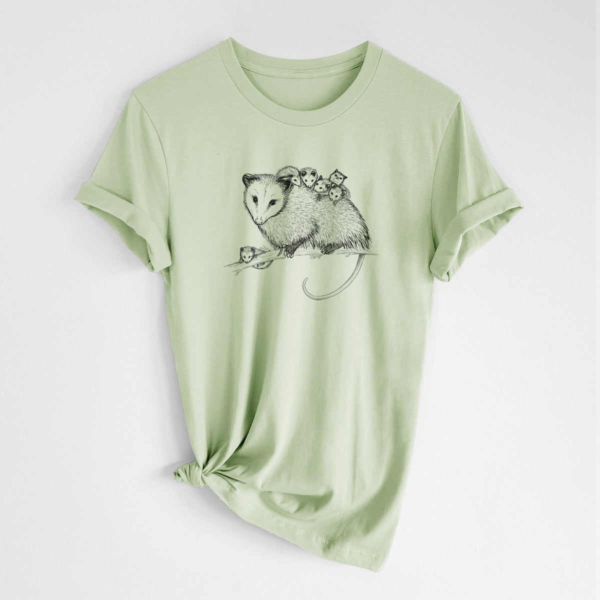 Spring green lightweight cotton t-shirt laid flat with the sleeves rolled, printed with a black ink illustration of a mother opossum on a branch carrying her babies on her back.
