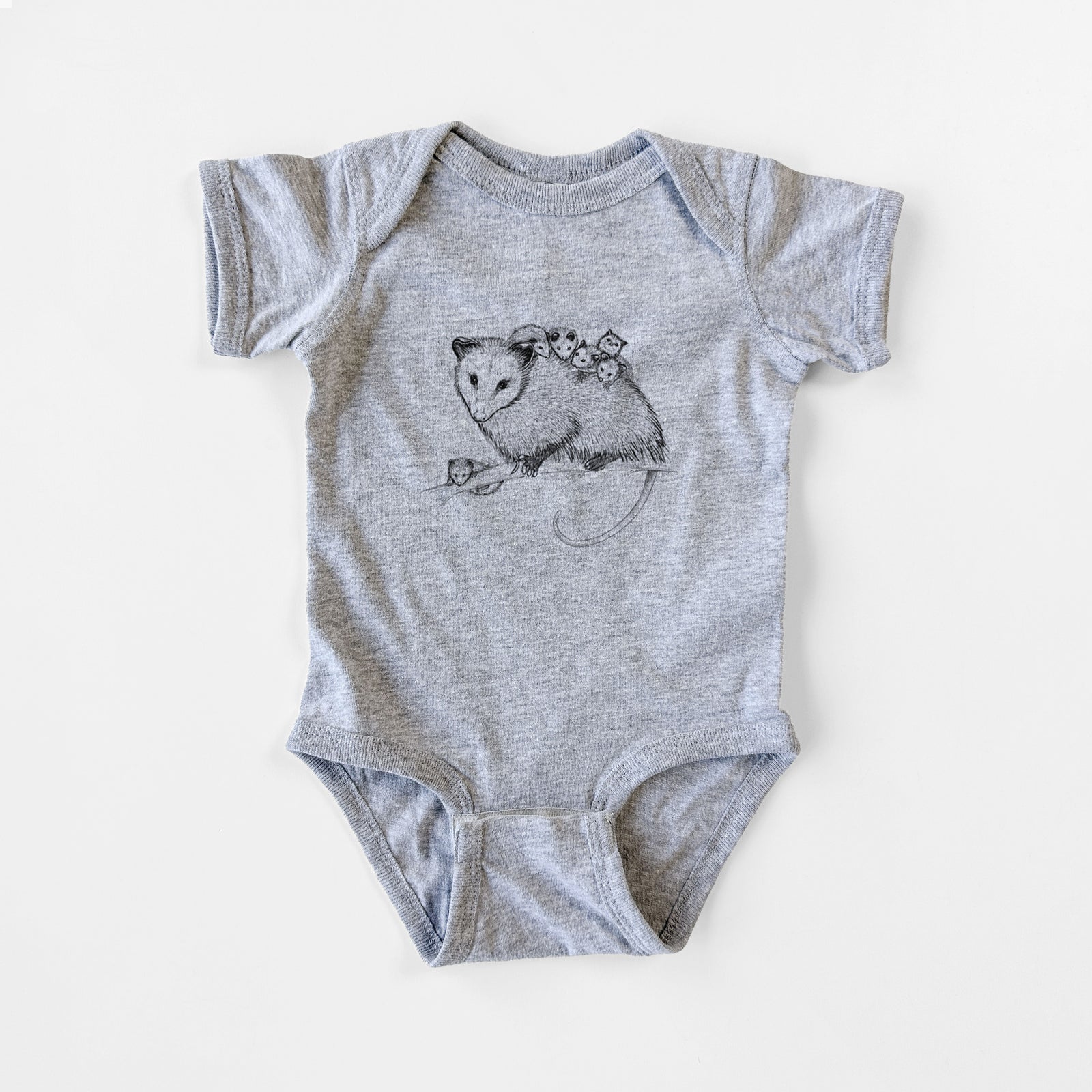 Grey baby bodysuit laid flat, printed with a black ink illustration of a mother opossum on a branch carrying her babies on her back.