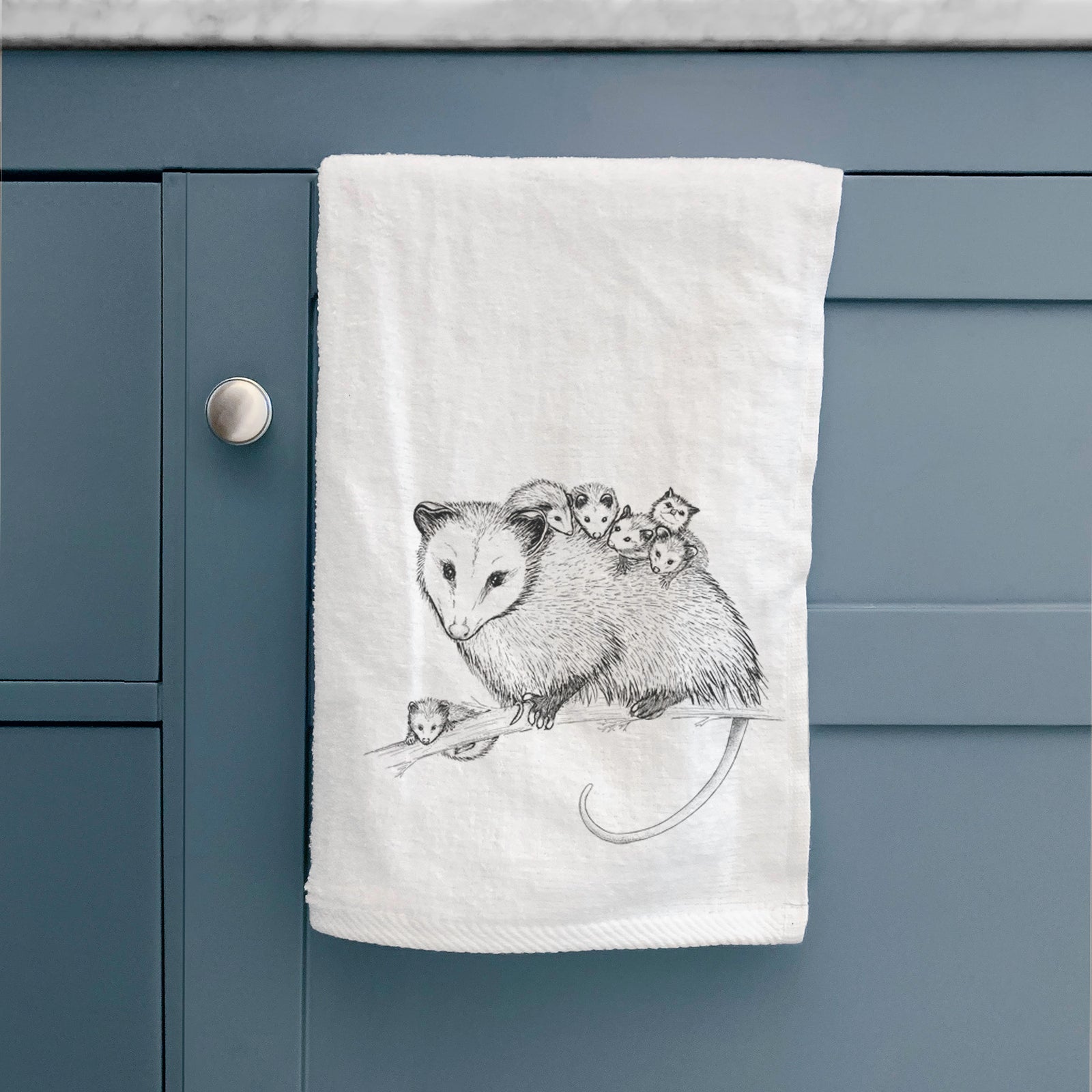 White hand towel printed with a black ink illustration of a mother opossum on a branch carrying her babies on her back.