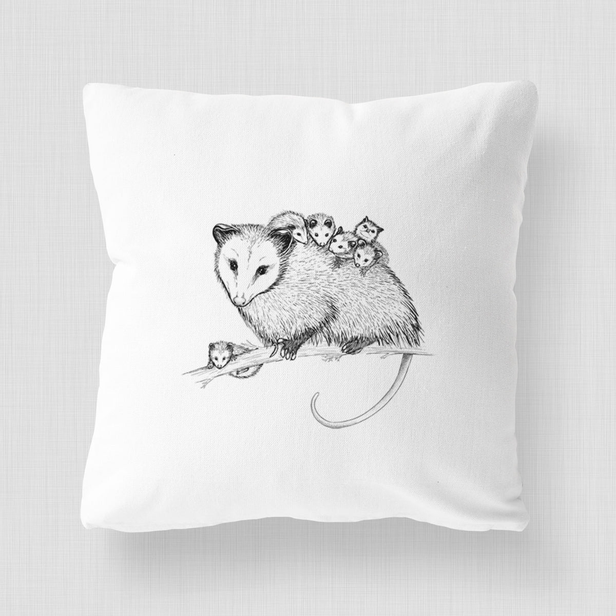 White pillow cover printed with a black ink illustration of a mother opossum on a branch carrying her babies on her back.