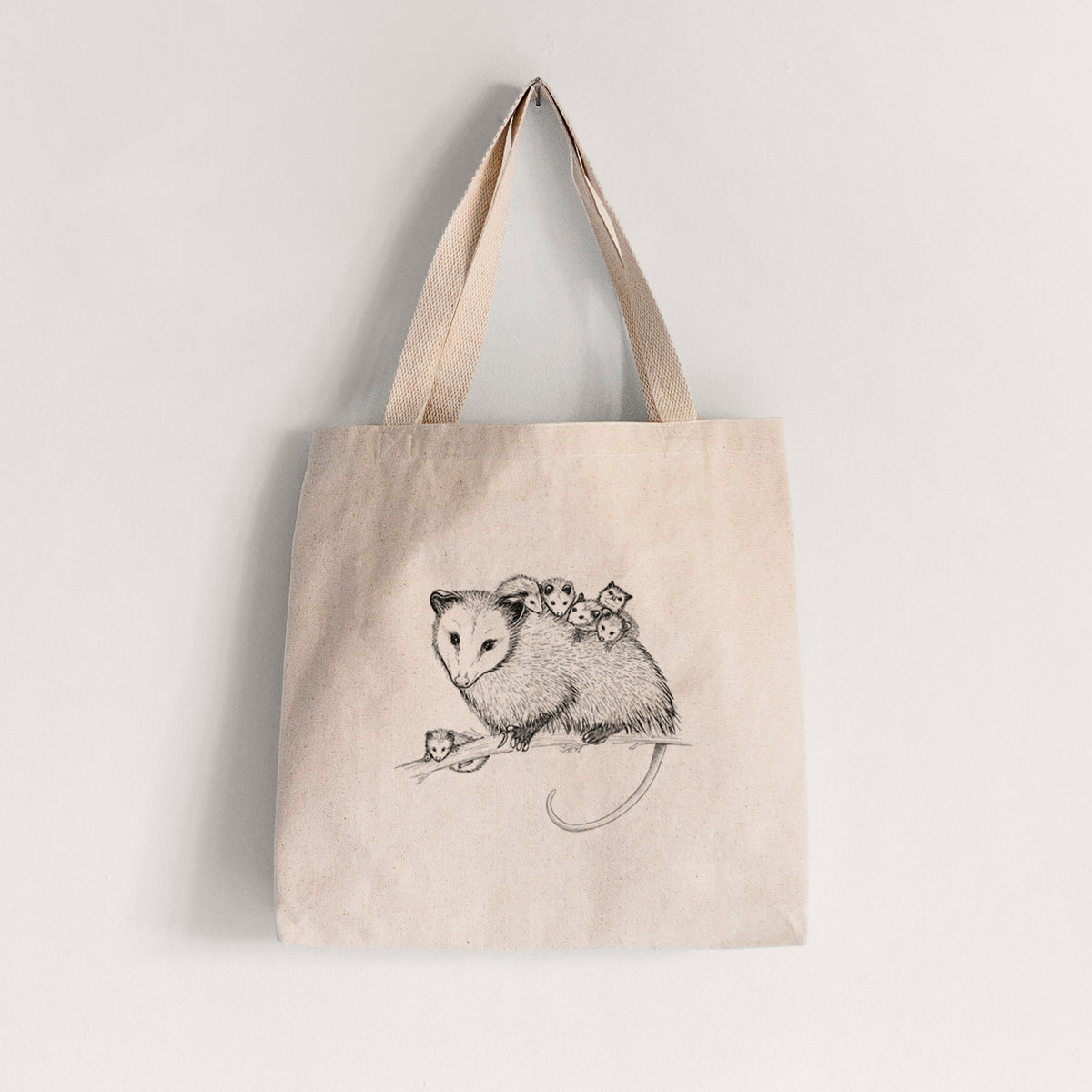Natural canvas tote bag printed with a black ink illustration of a mother opossum on a branch carrying her babies on her back.