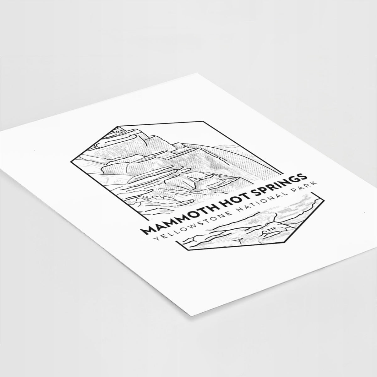 Art print of a black line art badge of the terraces at Mammoth Hot Springs, with the words Mammoth Hot Springs, Yellowstone National Park, lying at an angle on a white surface.