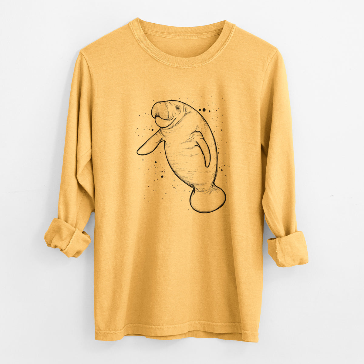 Golden wheat yellow Comfort Colors long sleeve shirt laid flat with the cuffs rolled, printed with a black ink line drawing of a manatee swimming, with ink splatters.
