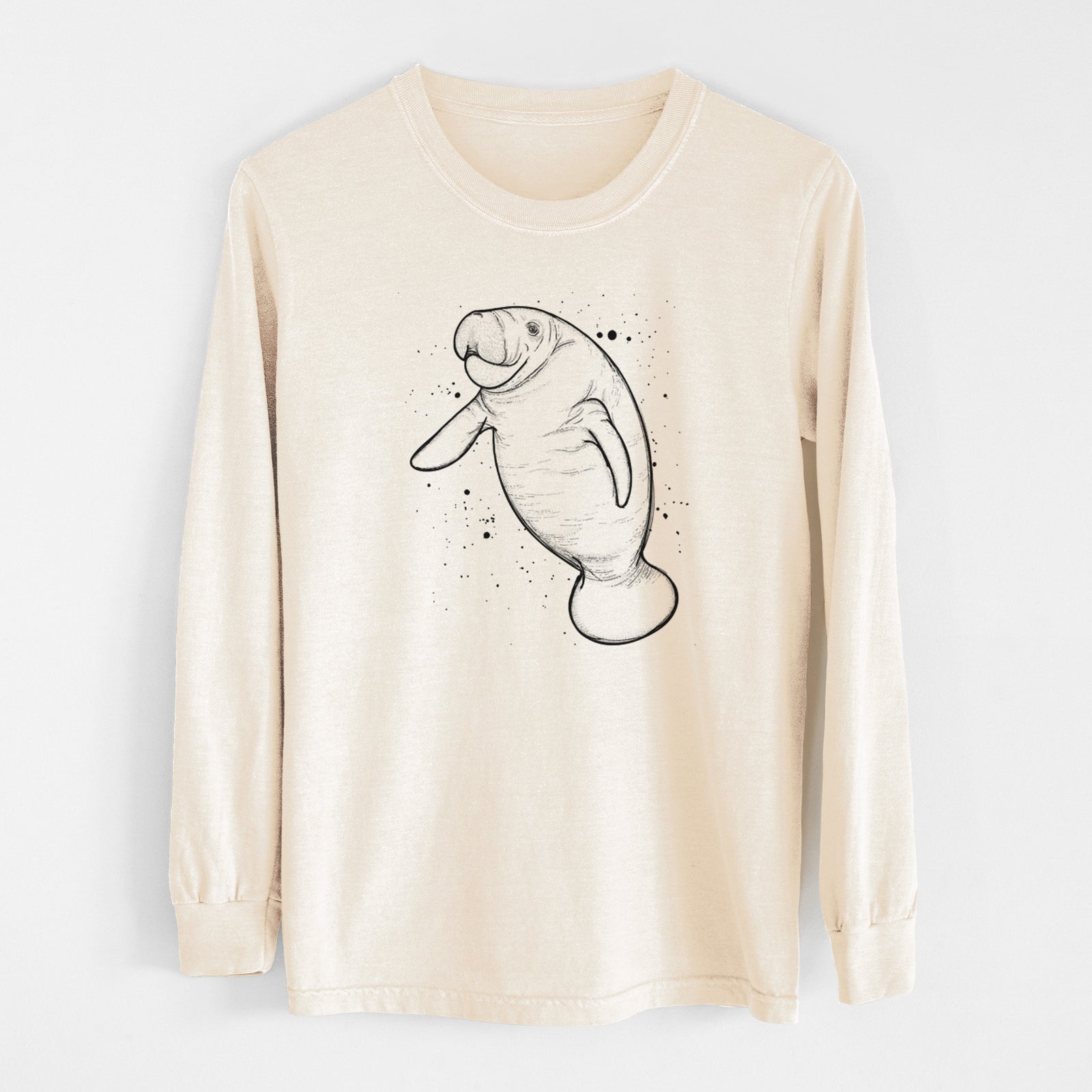 Ivory Comfort Colors long sleeve shirt laid flat, printed with a black ink line drawing of a manatee swimming, with ink splatters.